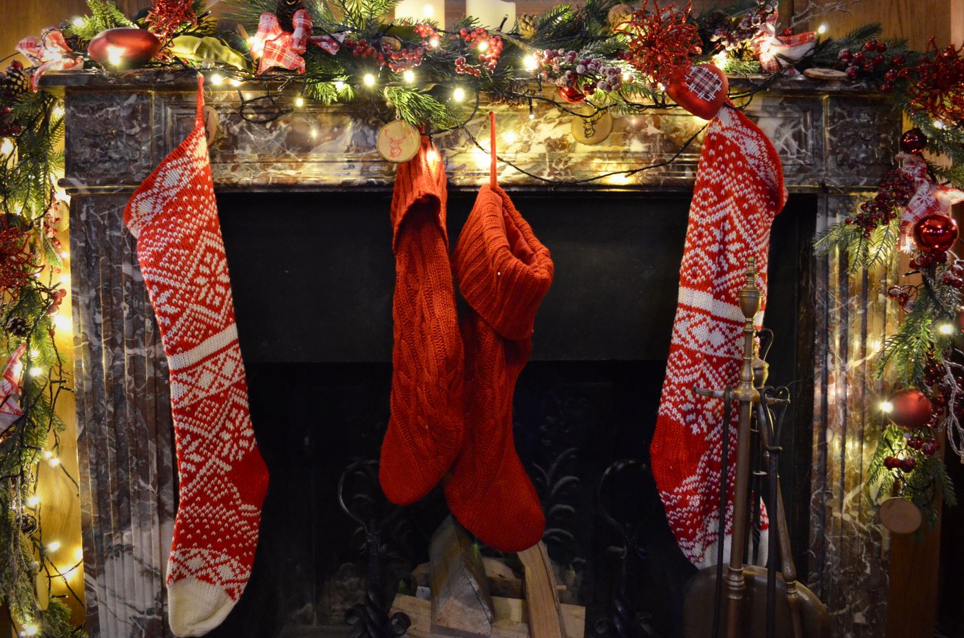 Christmas stockings hanging beneath a decorated fireplace mantel