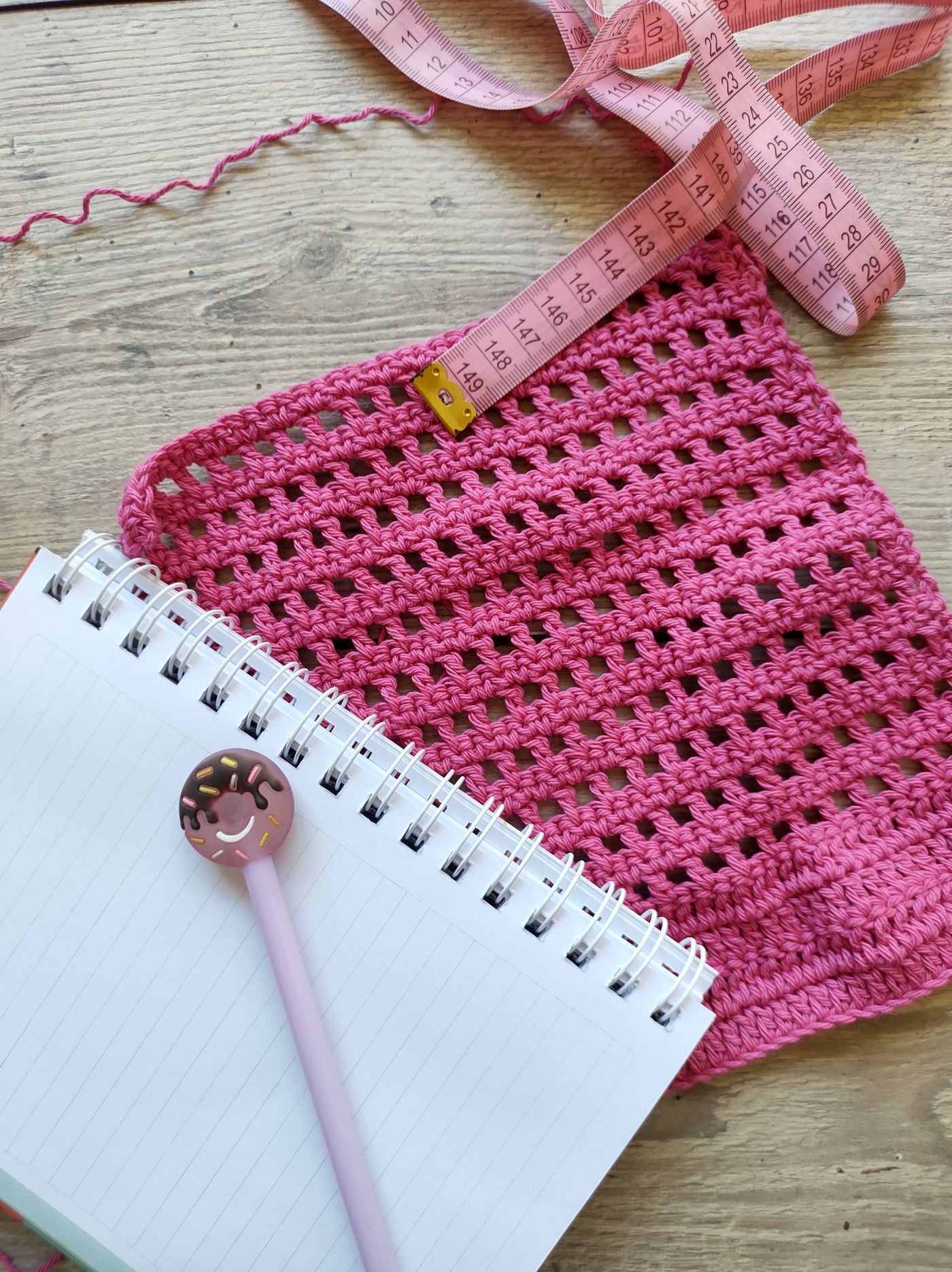 Crochet work beside a notebook and tape measure