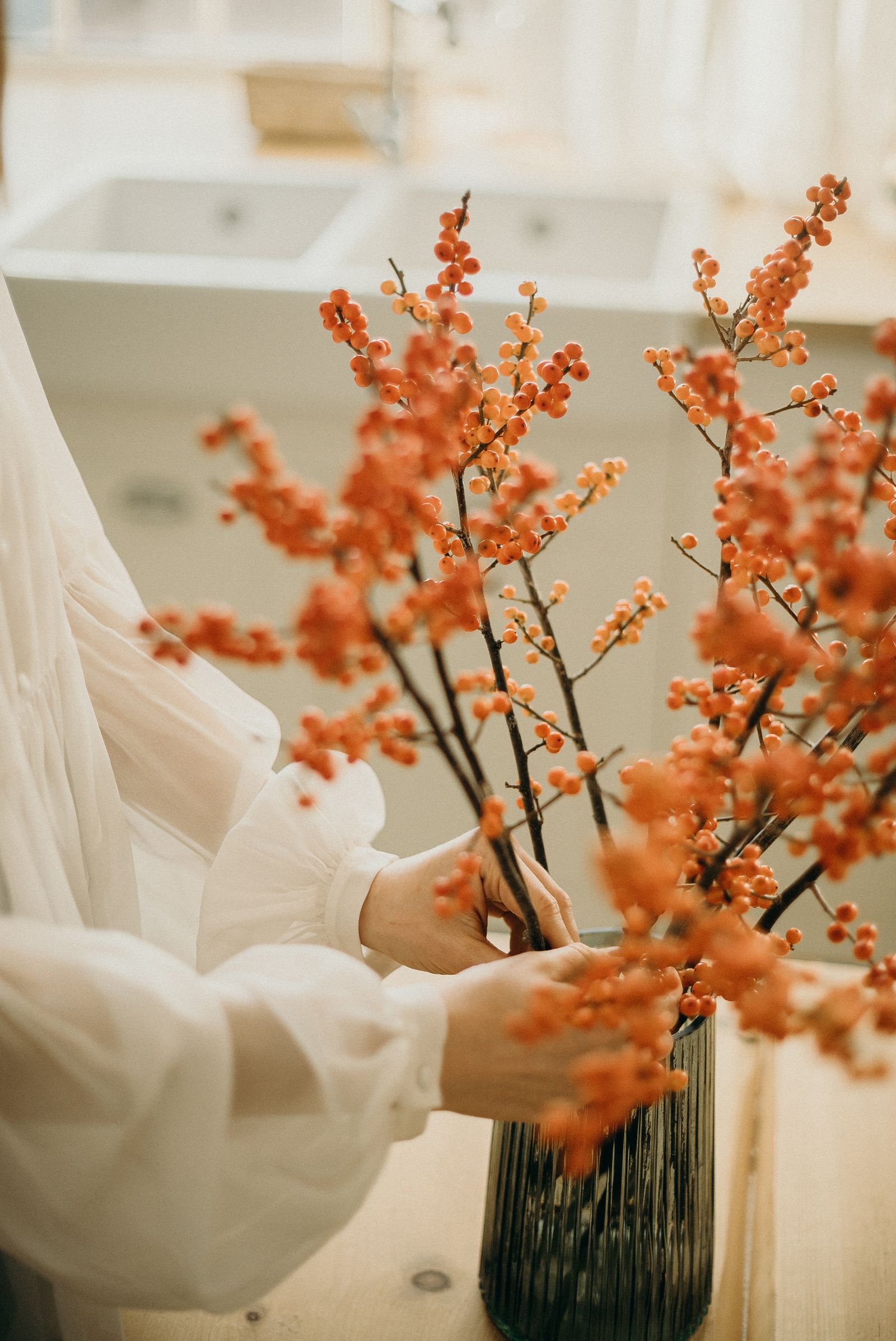 Hands arranging autumn stems in a vase
