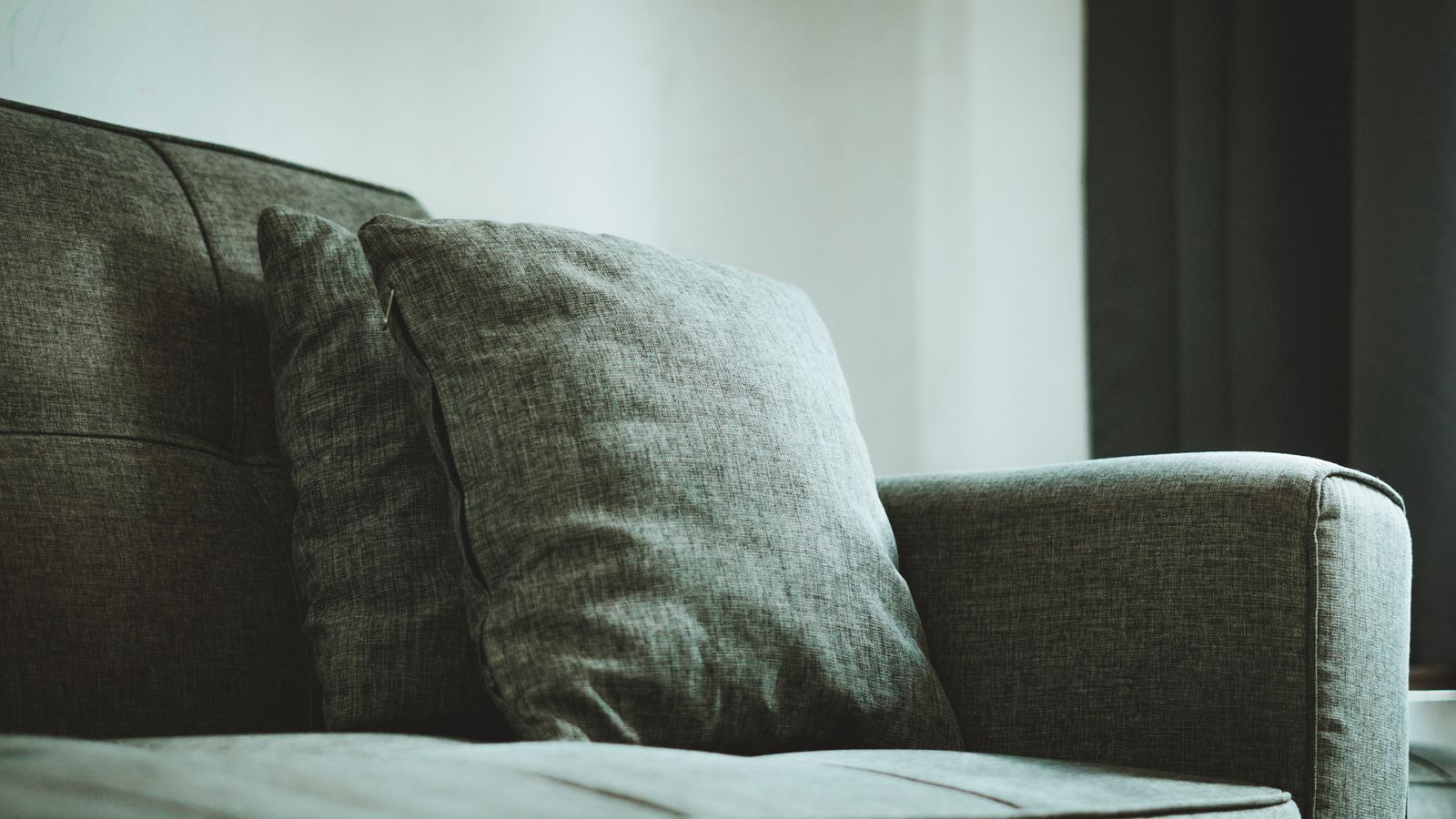 A textured pale-green cushion beside a sofa arm