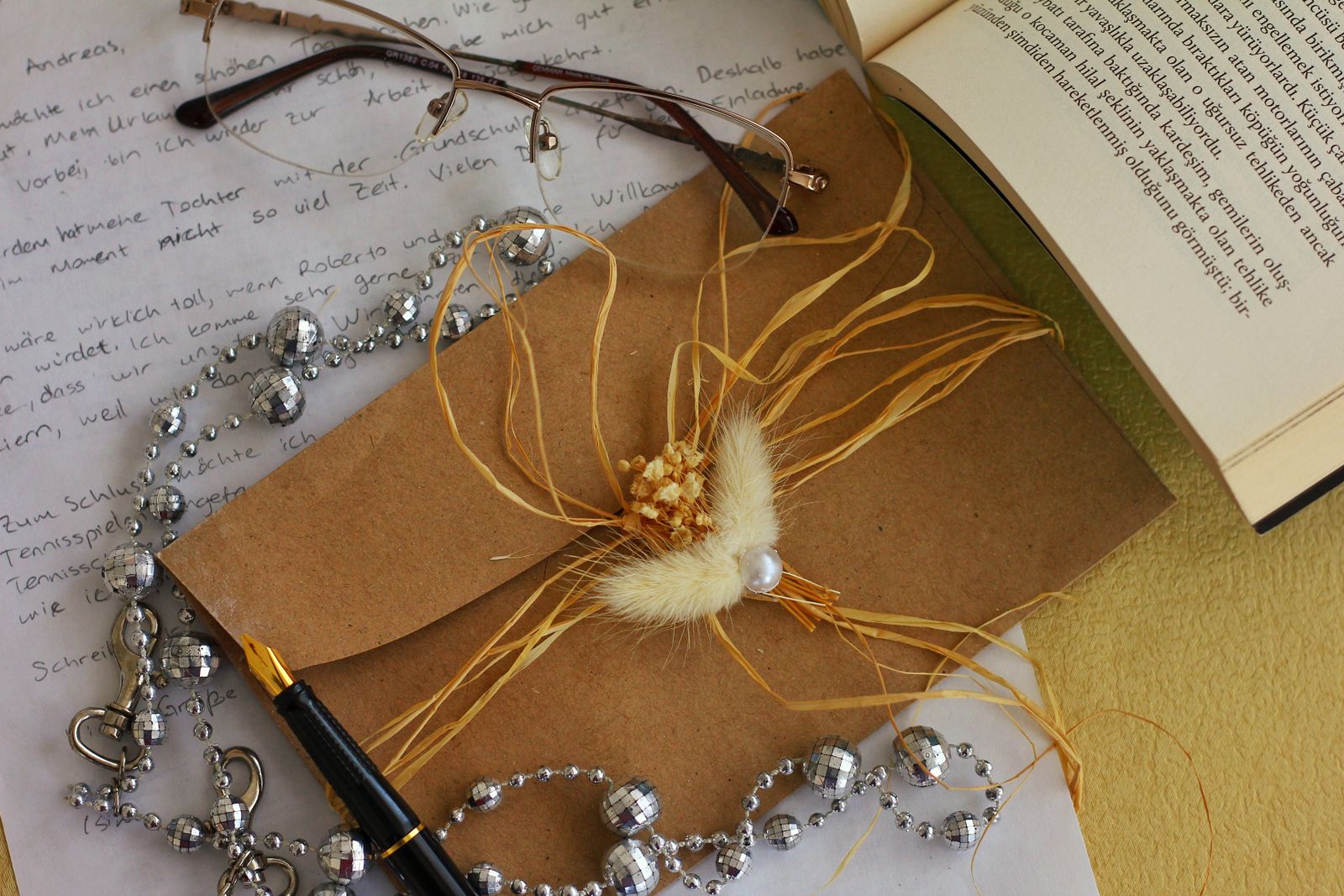 Decorated envelopes and handwritten paper beside a book and glasses