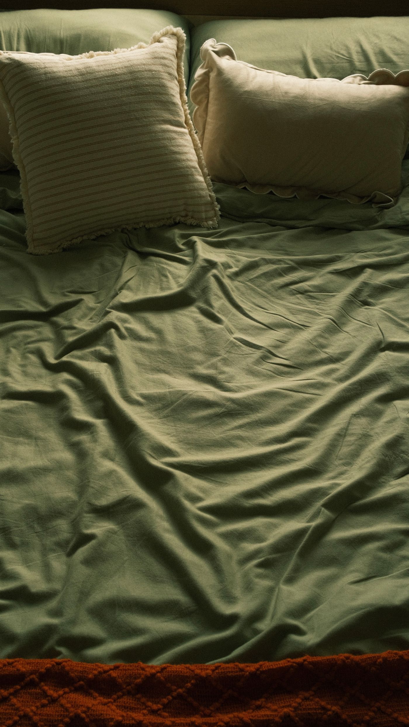 Olive-colored bedding and cushions shown close up
