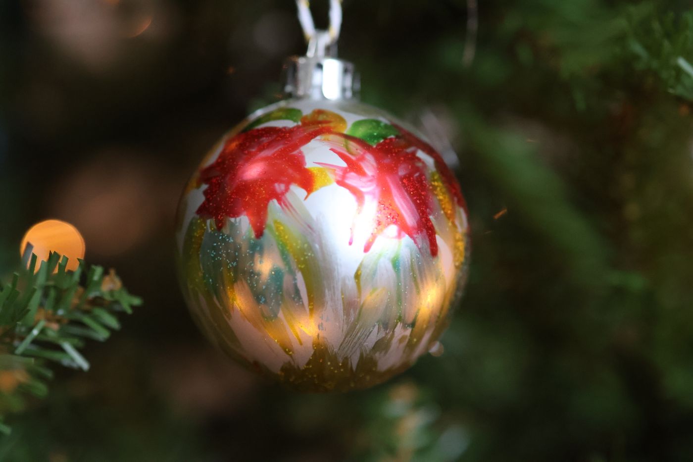 A painted floral ornament hanging on a tree