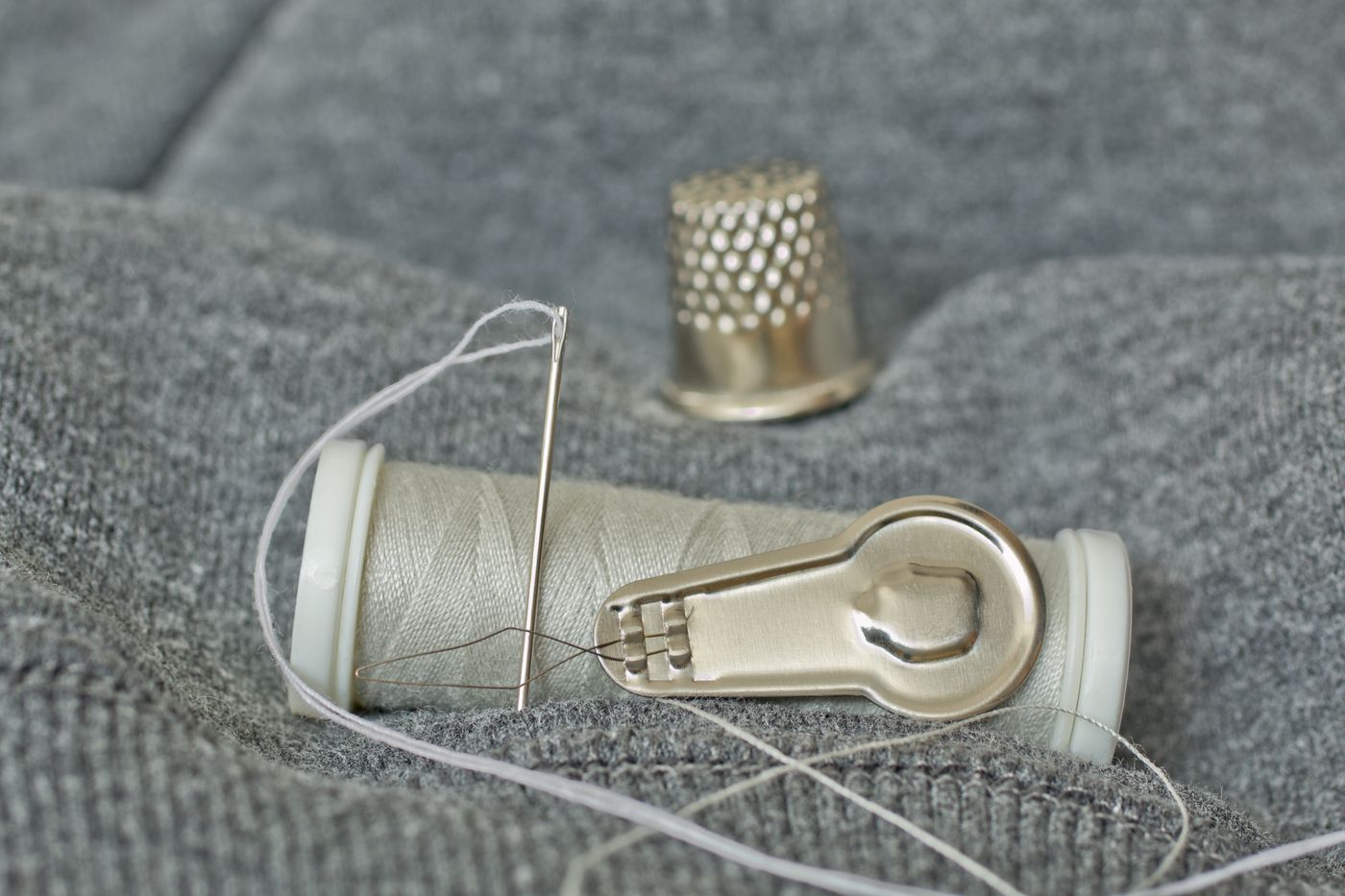 Needle thread and thimble beside a small sewing case