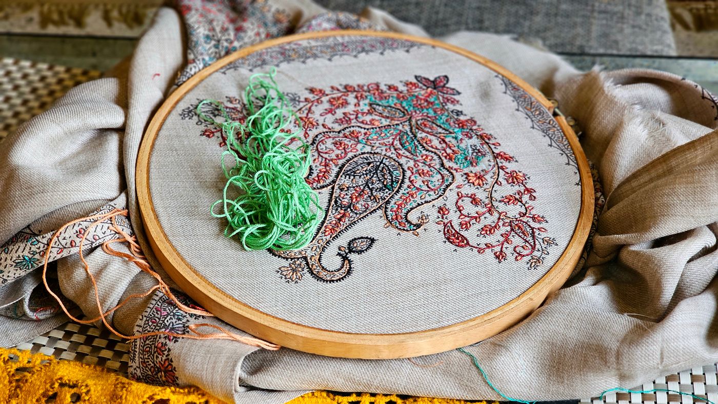 Loose green thread beside an unfinished embroidery hoop