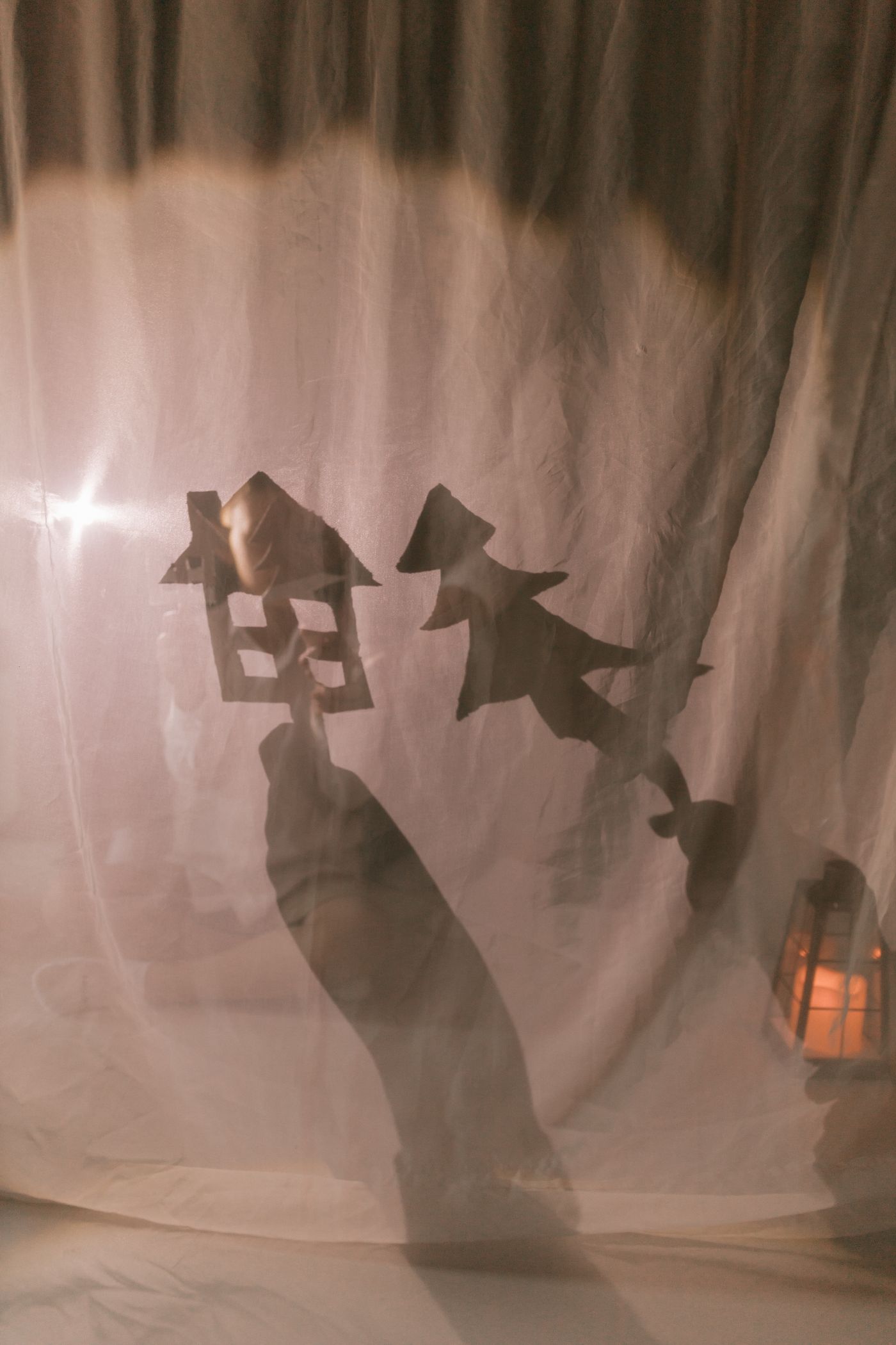 A house and character silhouette in a shadow-puppet scene