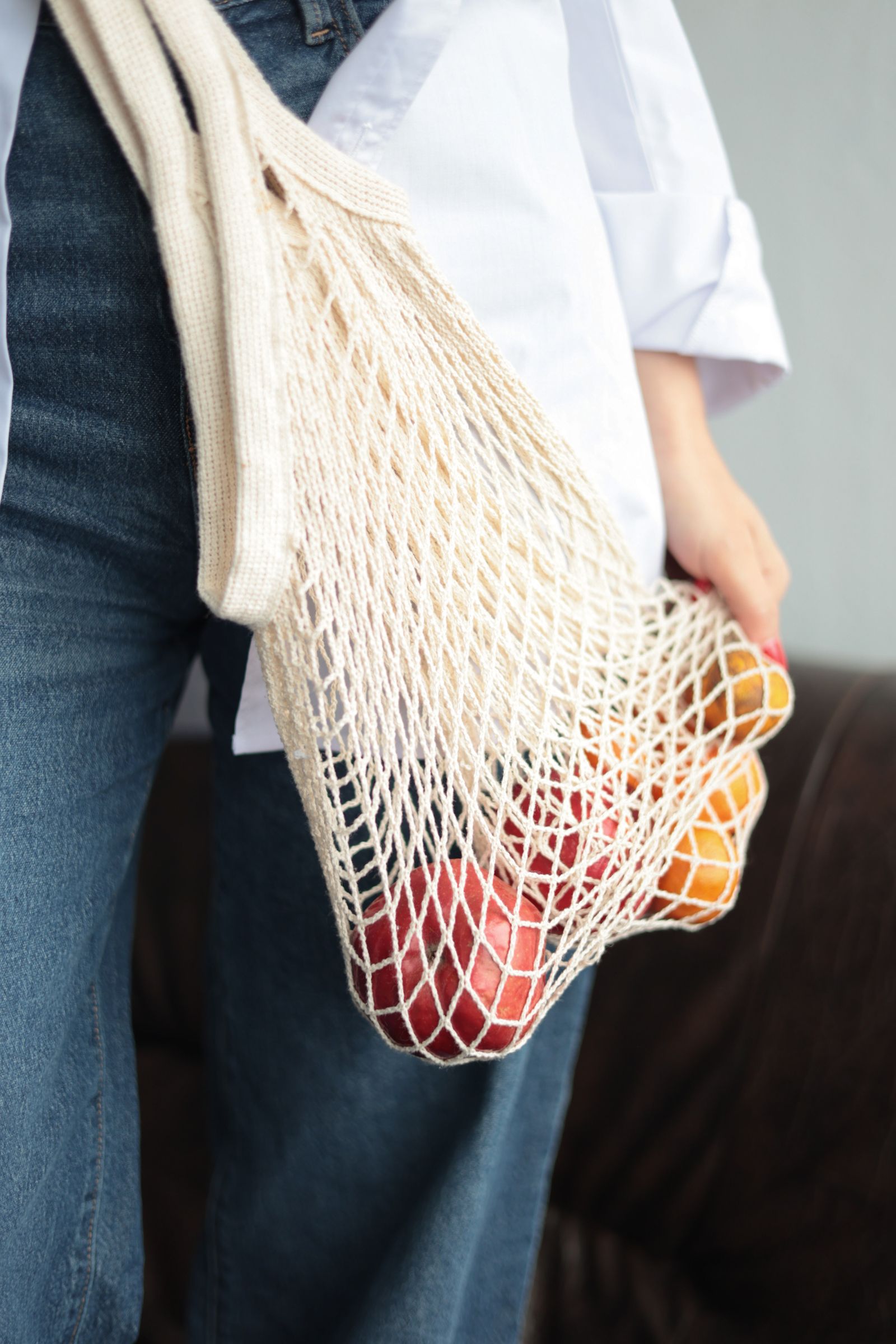 A person carrying fruit in a reusable mesh bag