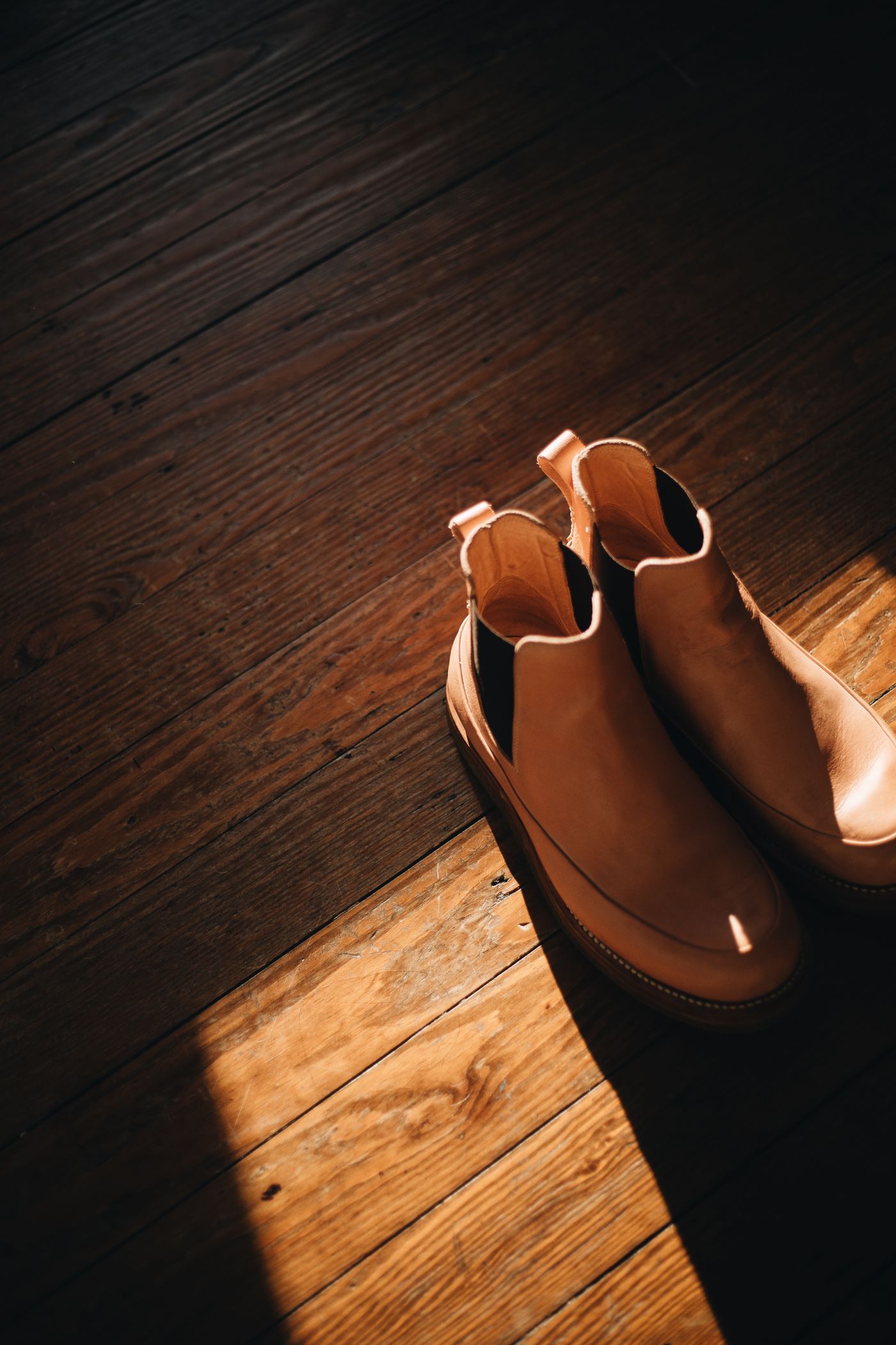 Leather boots resting on a wood floor as footwear context