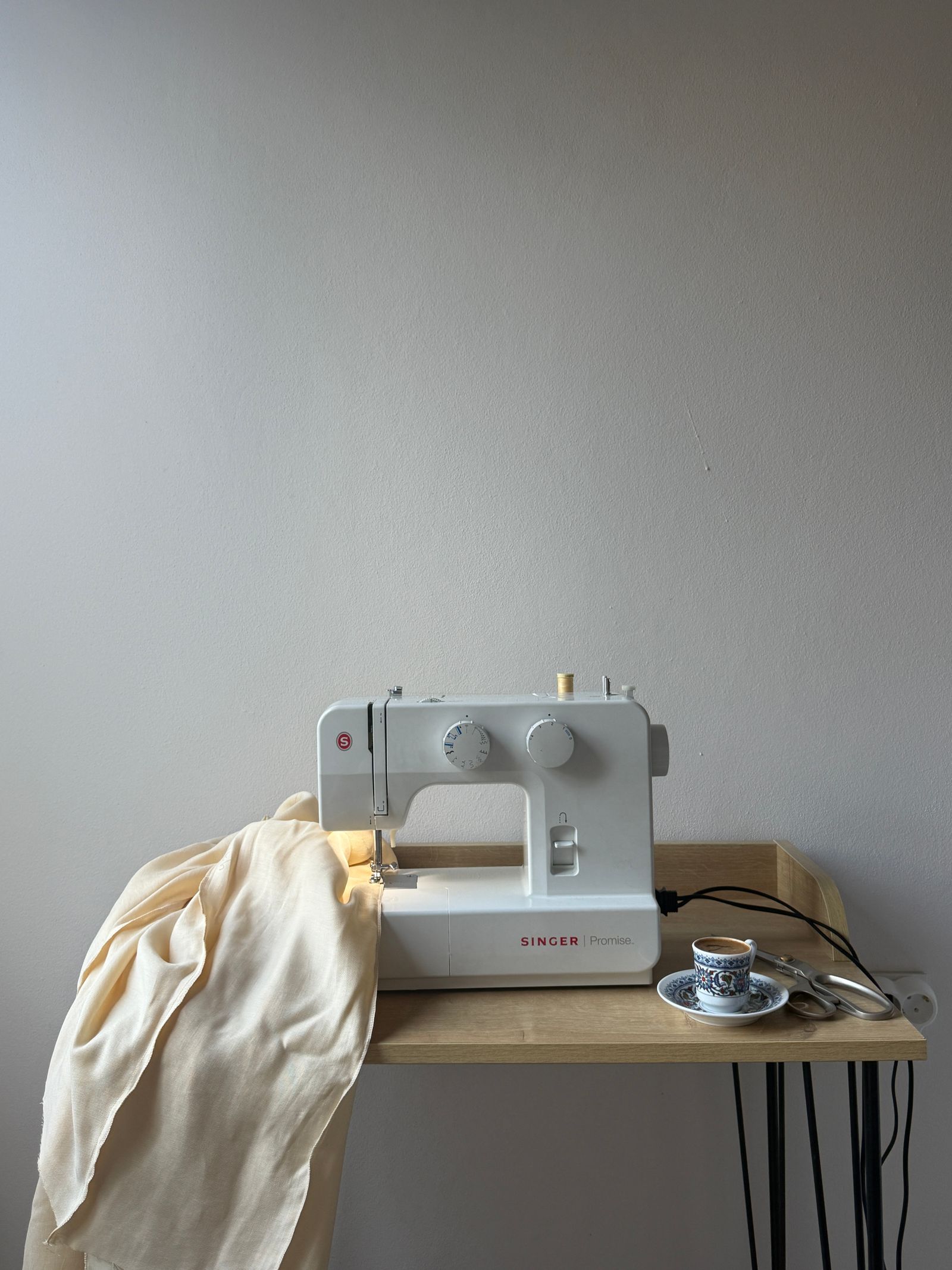 A sewing machine with fabric draped across a small table