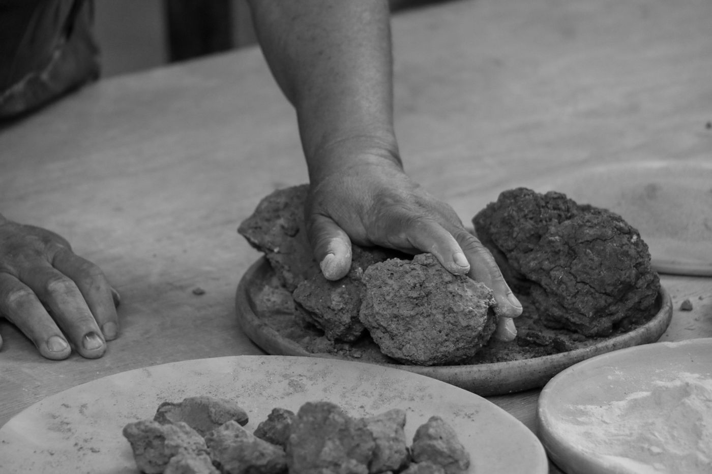 Black-and-white close-up of hands working clay