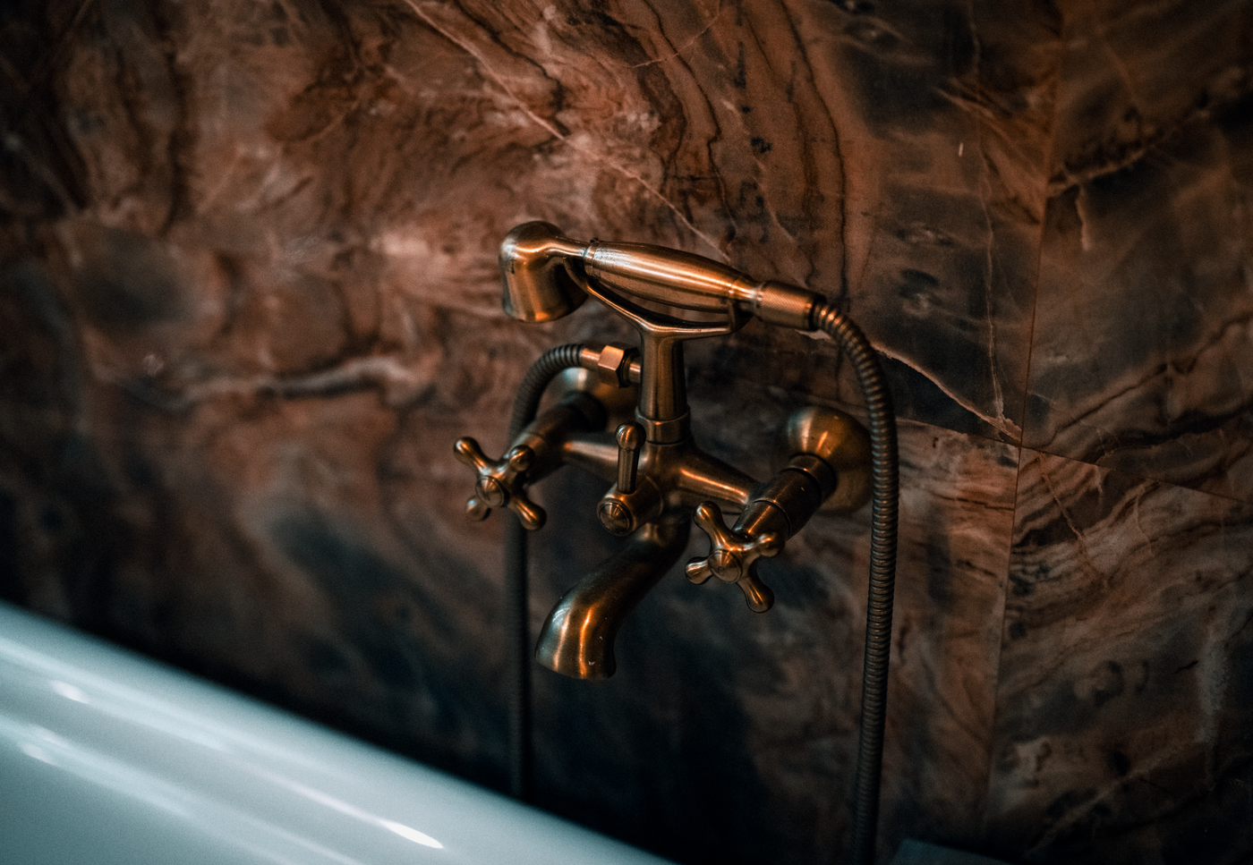 An ornate metallic faucet against a textured wall