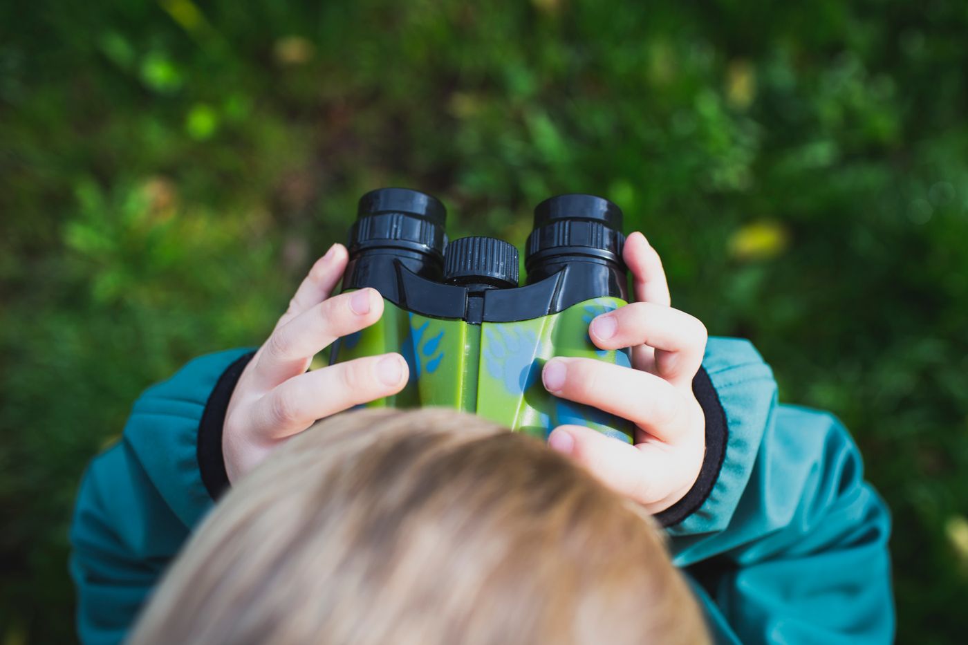 Close view of a child holding binoculars outside