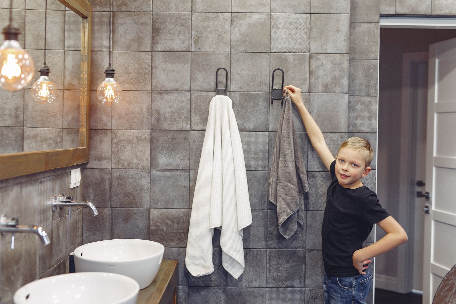 A clothed child reaching toward a high towel hook