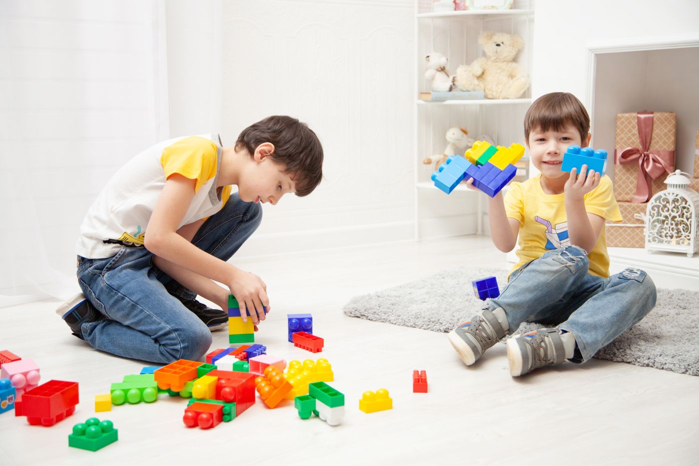 Two children building separately with colorful blocks