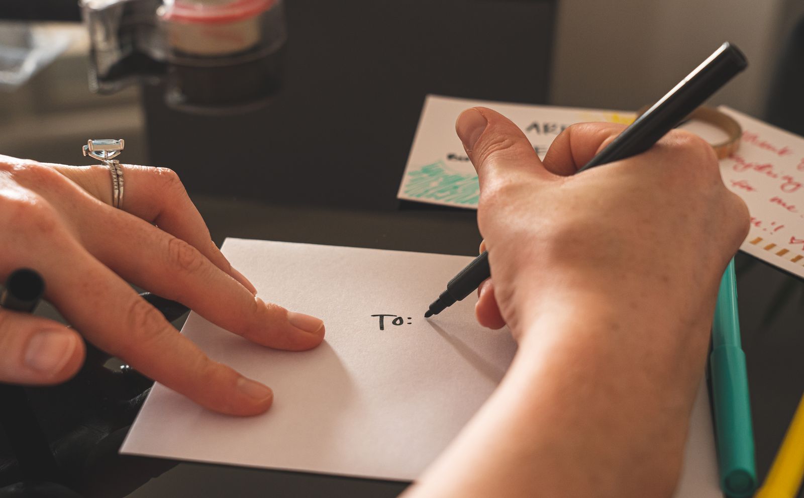 Hands addressing an envelope with a dark pen