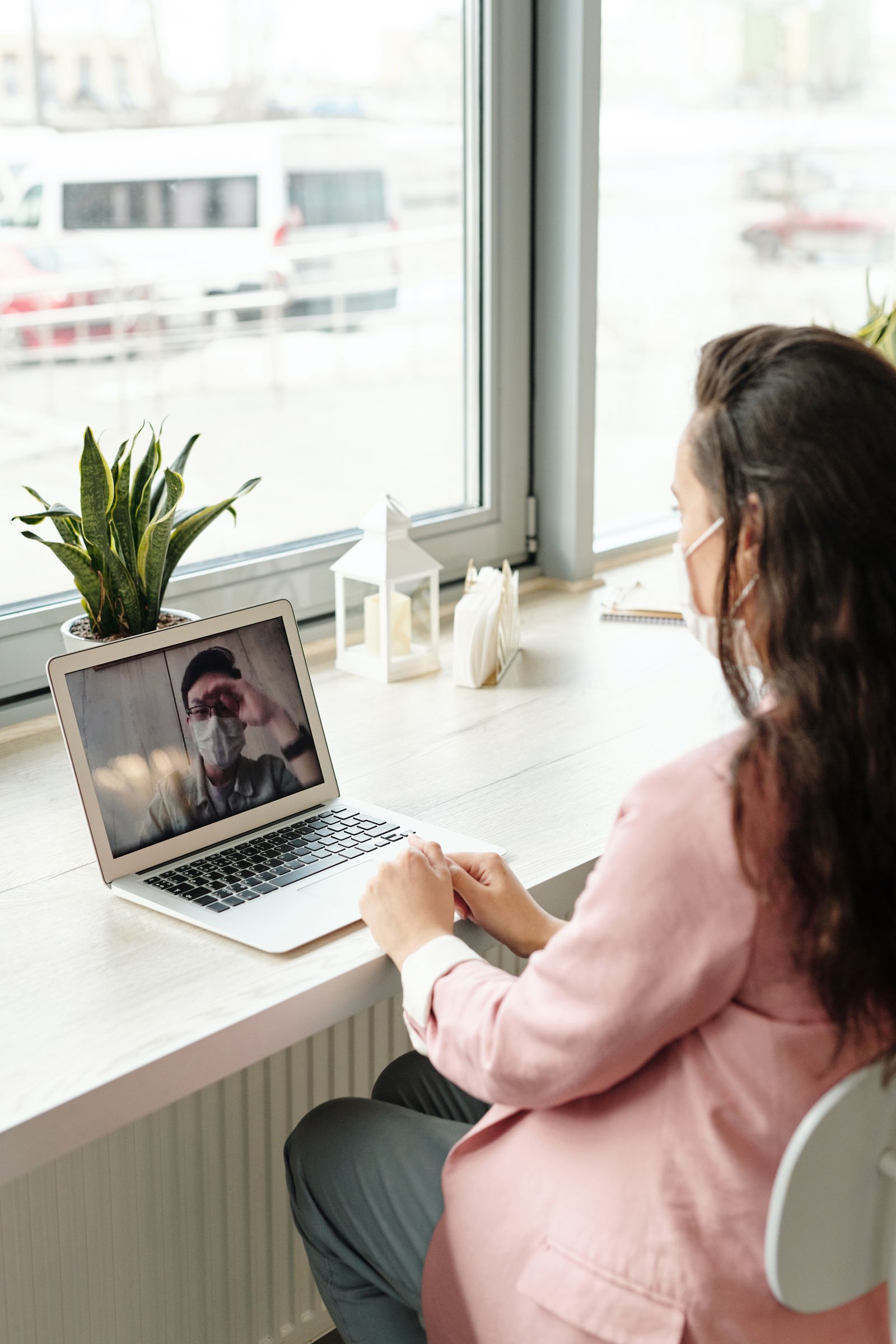 A person making a laptop video call beside a window