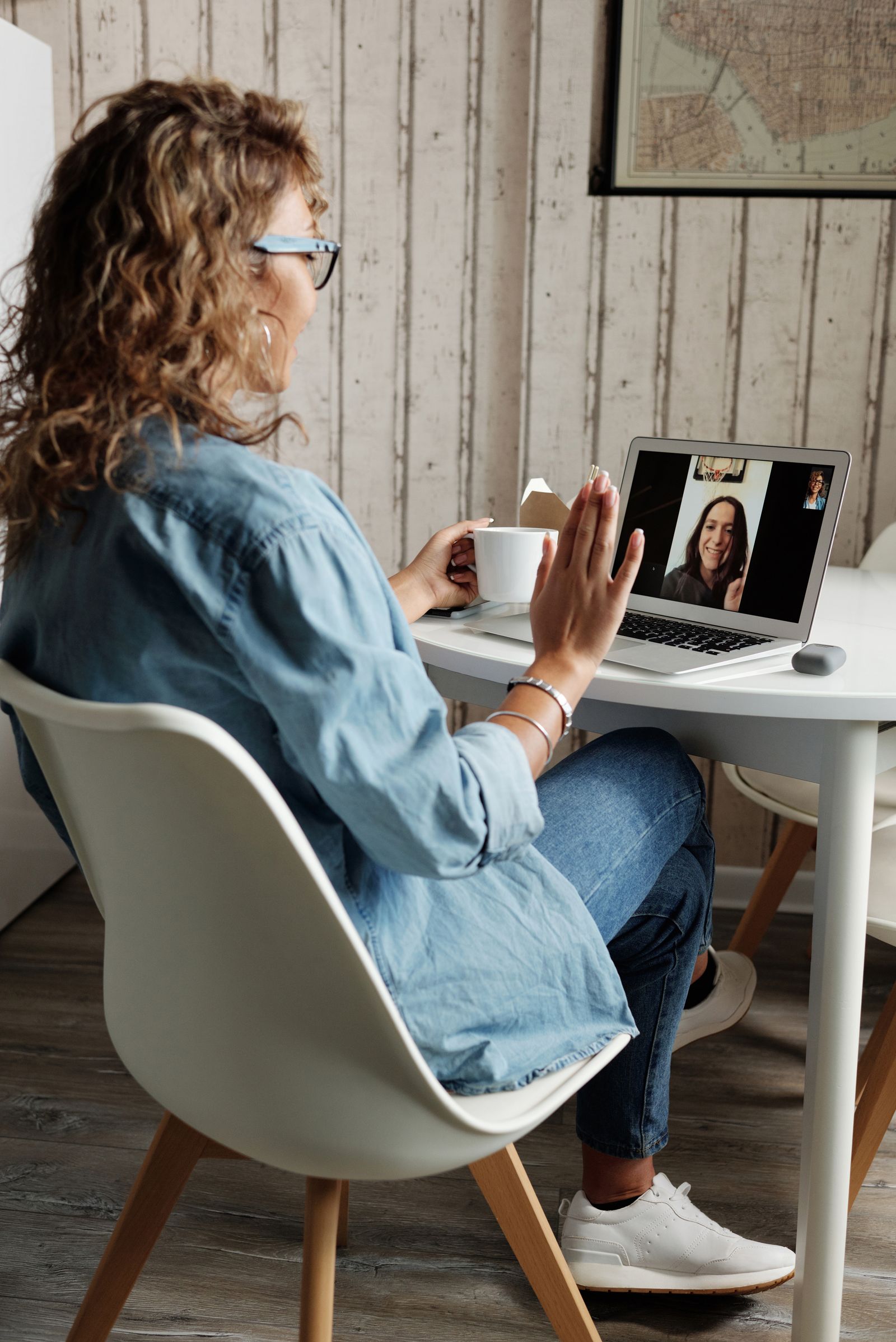 A person waving during a video call at a desk