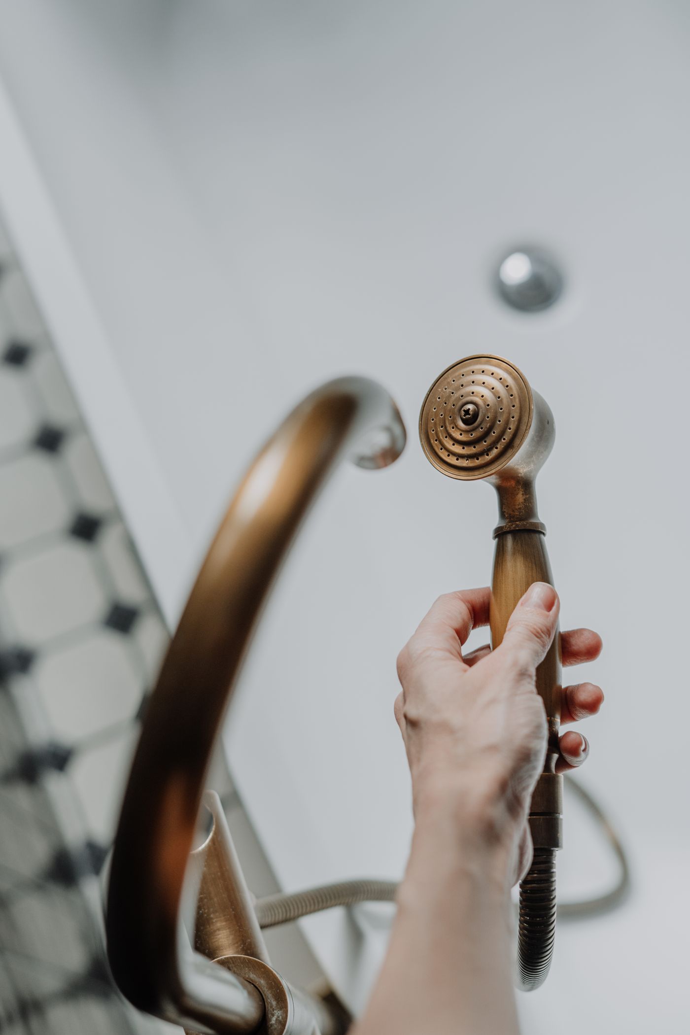 A hand holding a metallic shower fitting