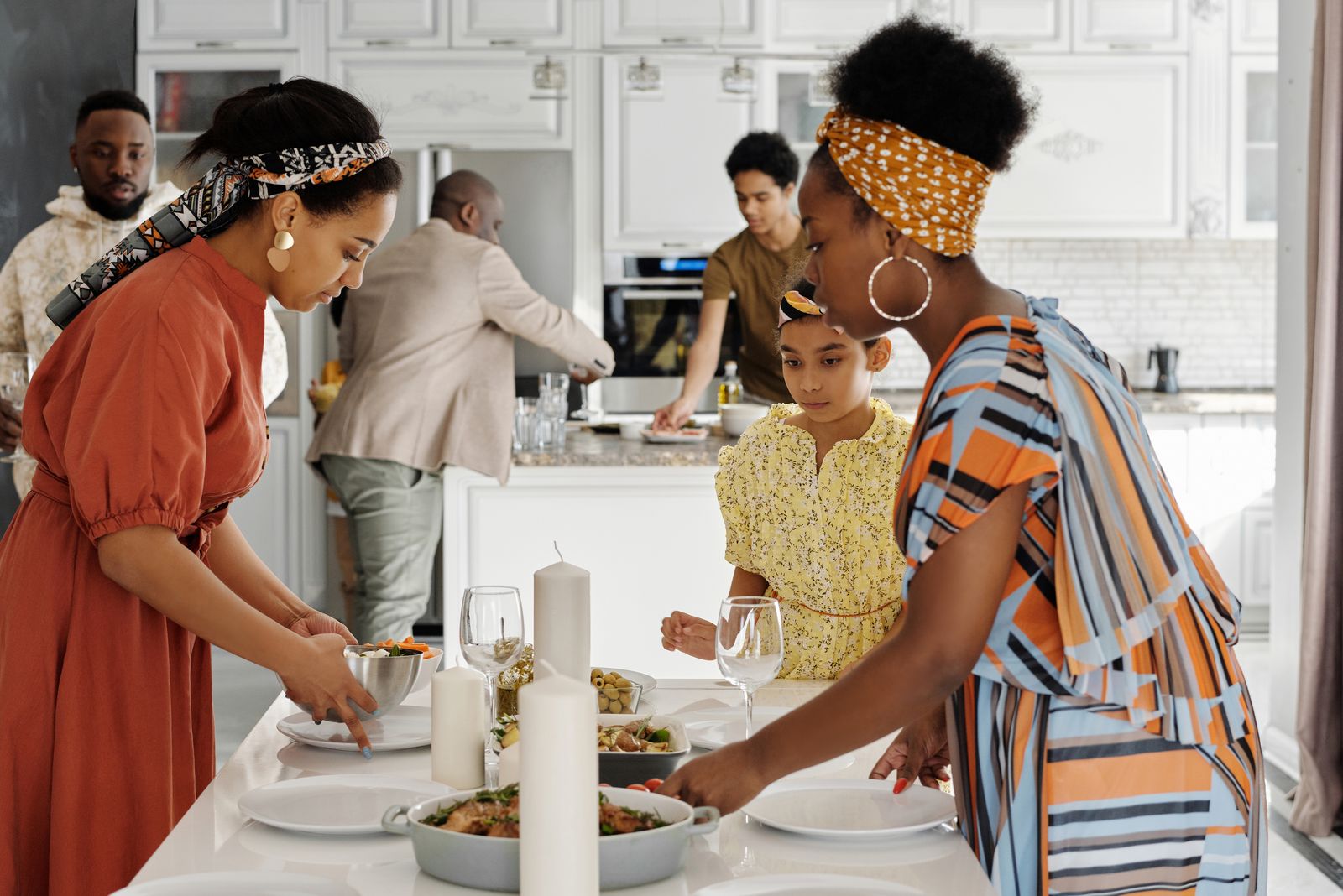 A family arranging plates and glasses on a dining table