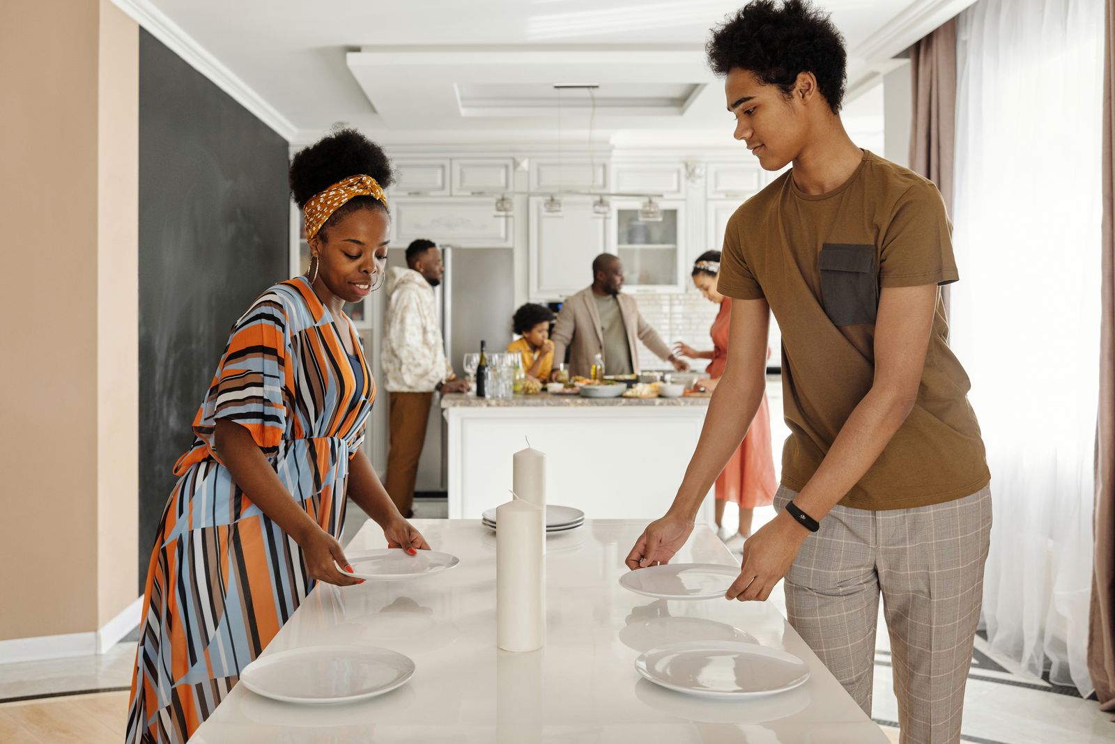 Two family members placing plates on a dining table