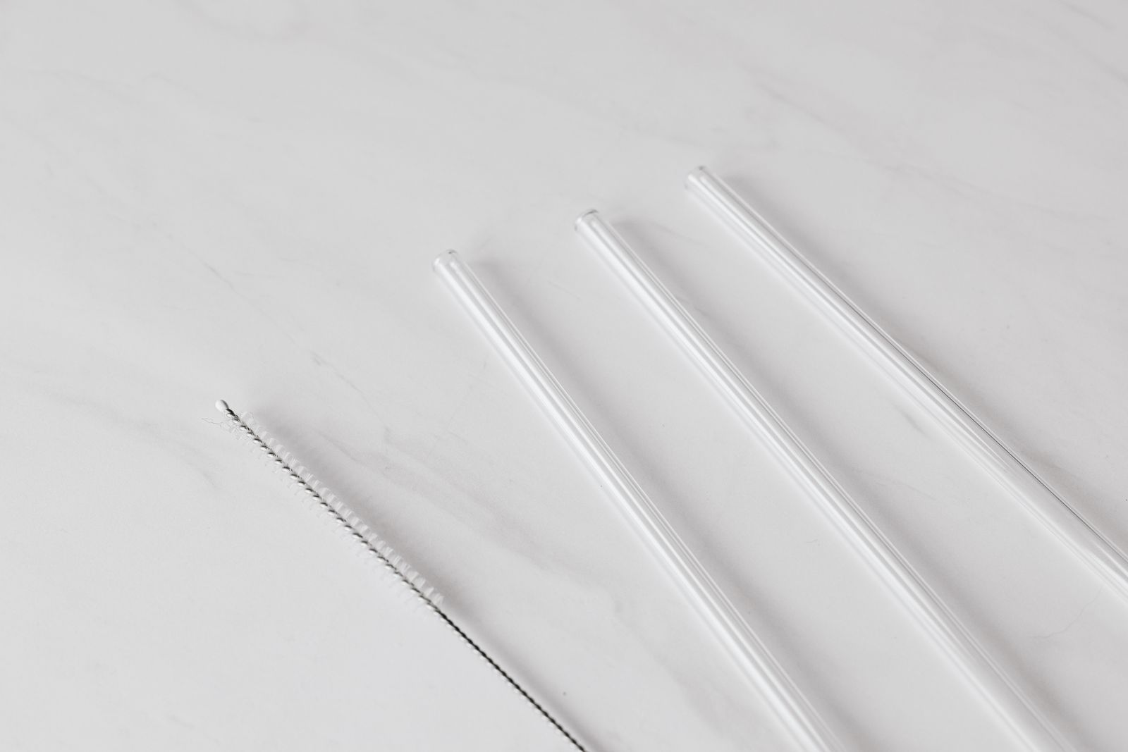 A narrow cleaning brush beside transparent drinking tubes