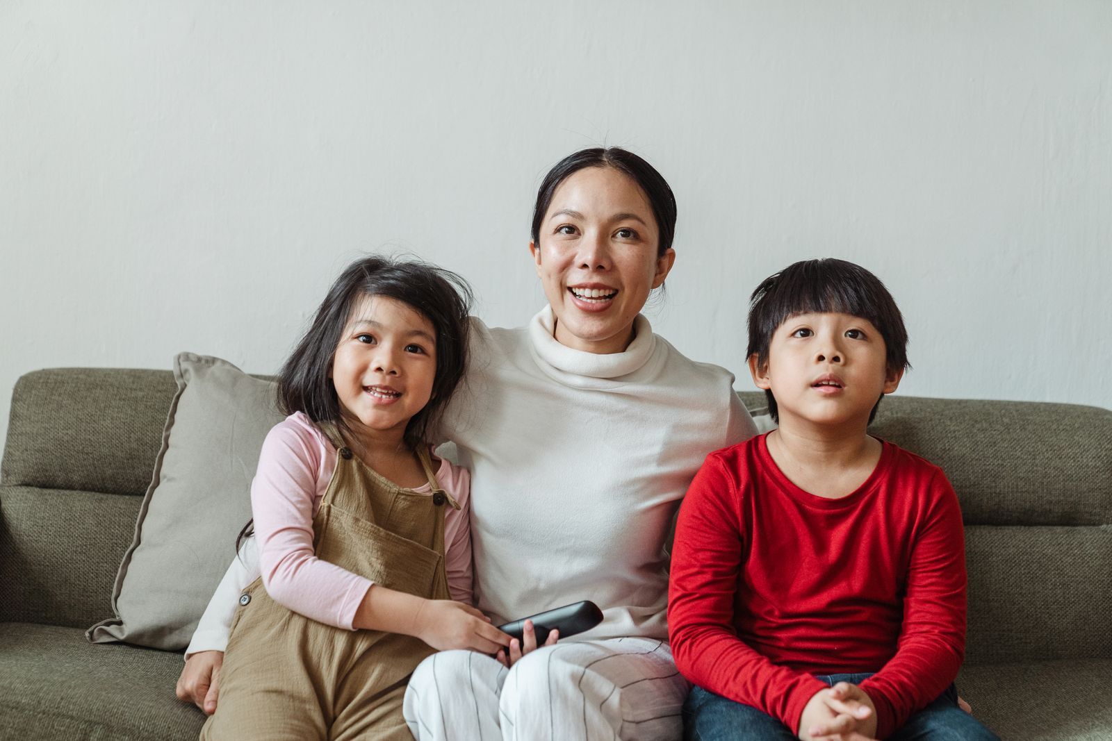 An adult and two children watching from a sofa