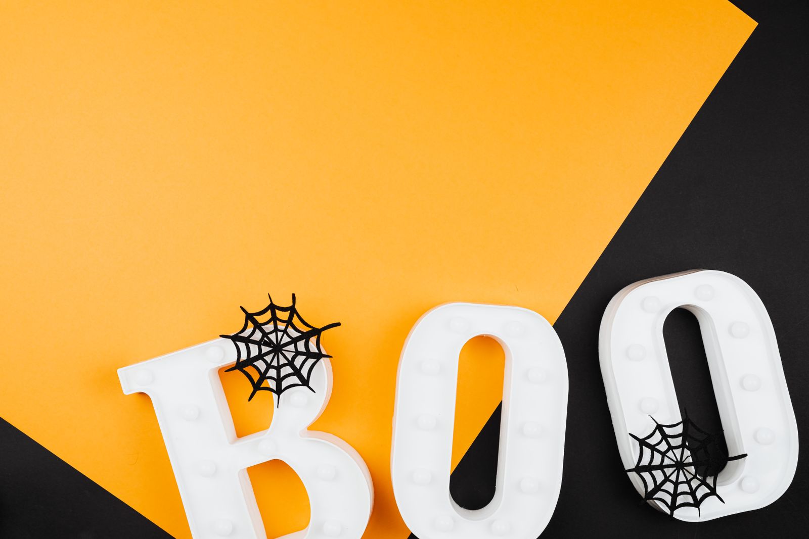 BOO letters and small web decorations on orange and black surfaces