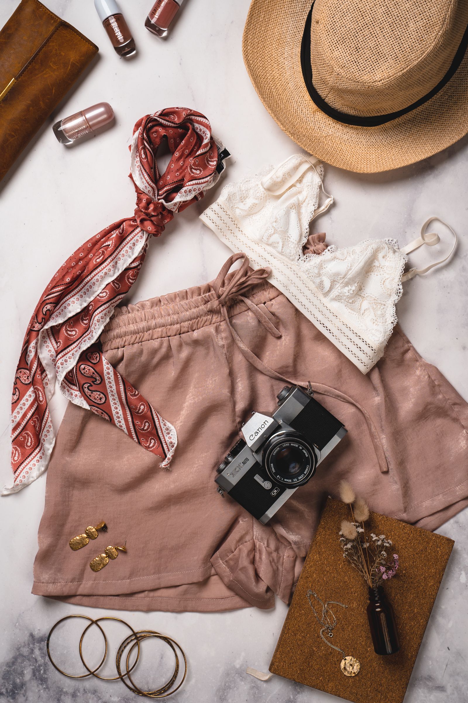 A scarf, hat, camera, and clothing arranged together