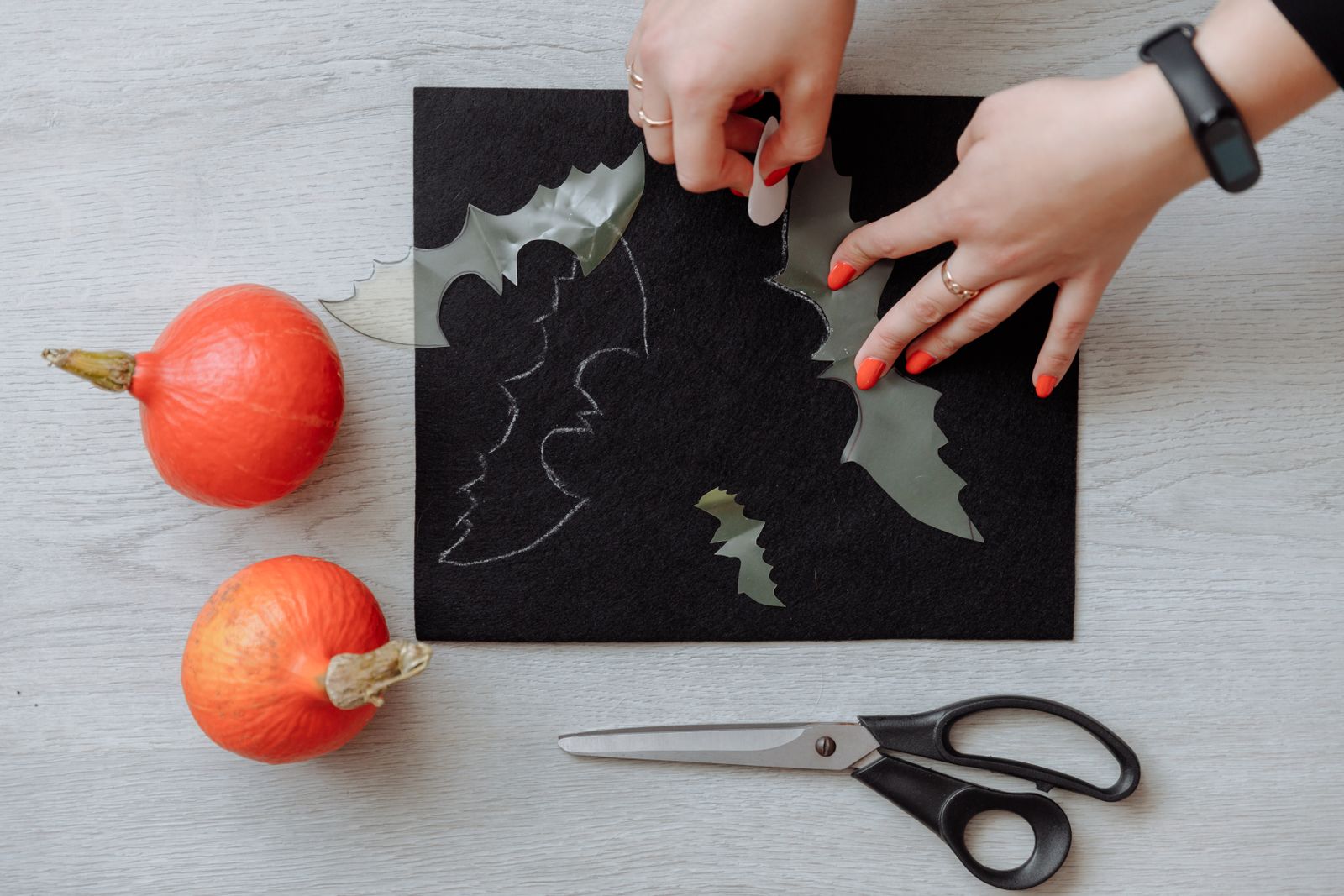 Hands cutting black paper for Halloween decorations