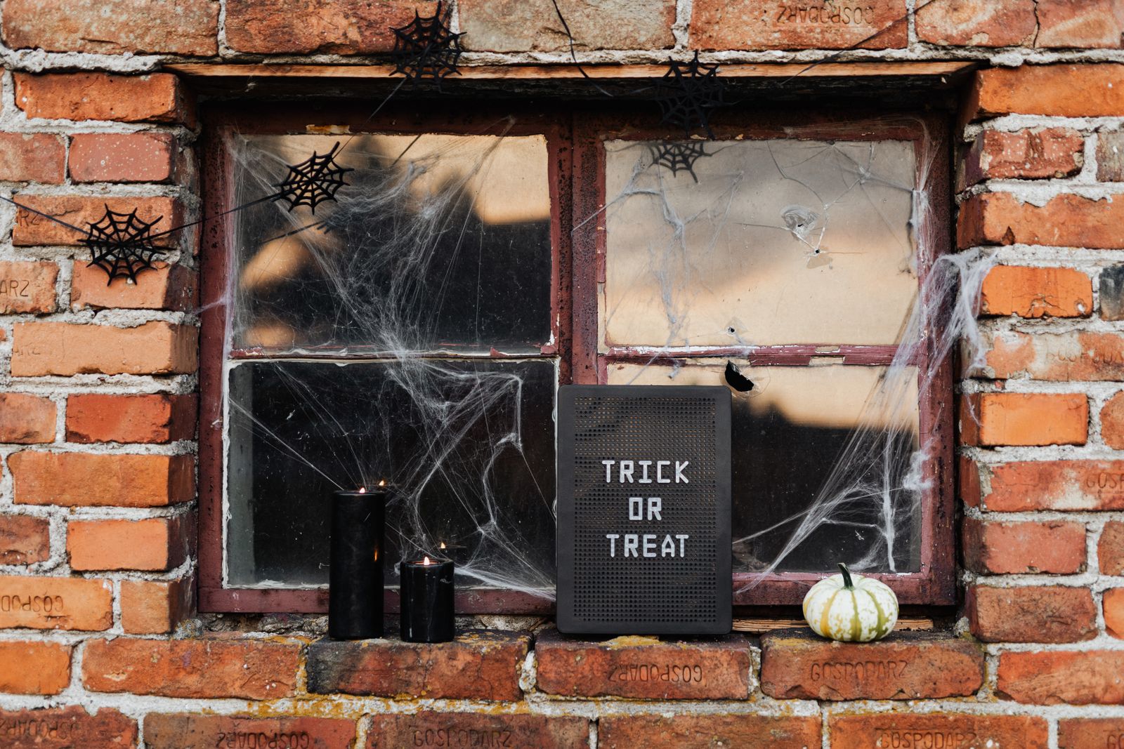 A window decorated with a trick-or-treat sign and cobwebs