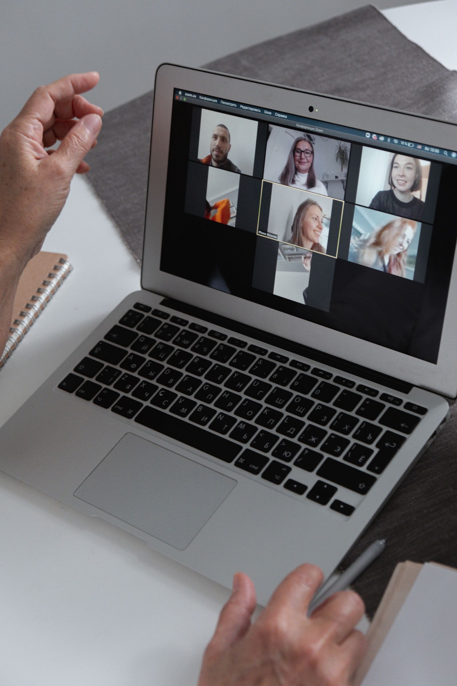 Hands beside a laptop showing a group video call