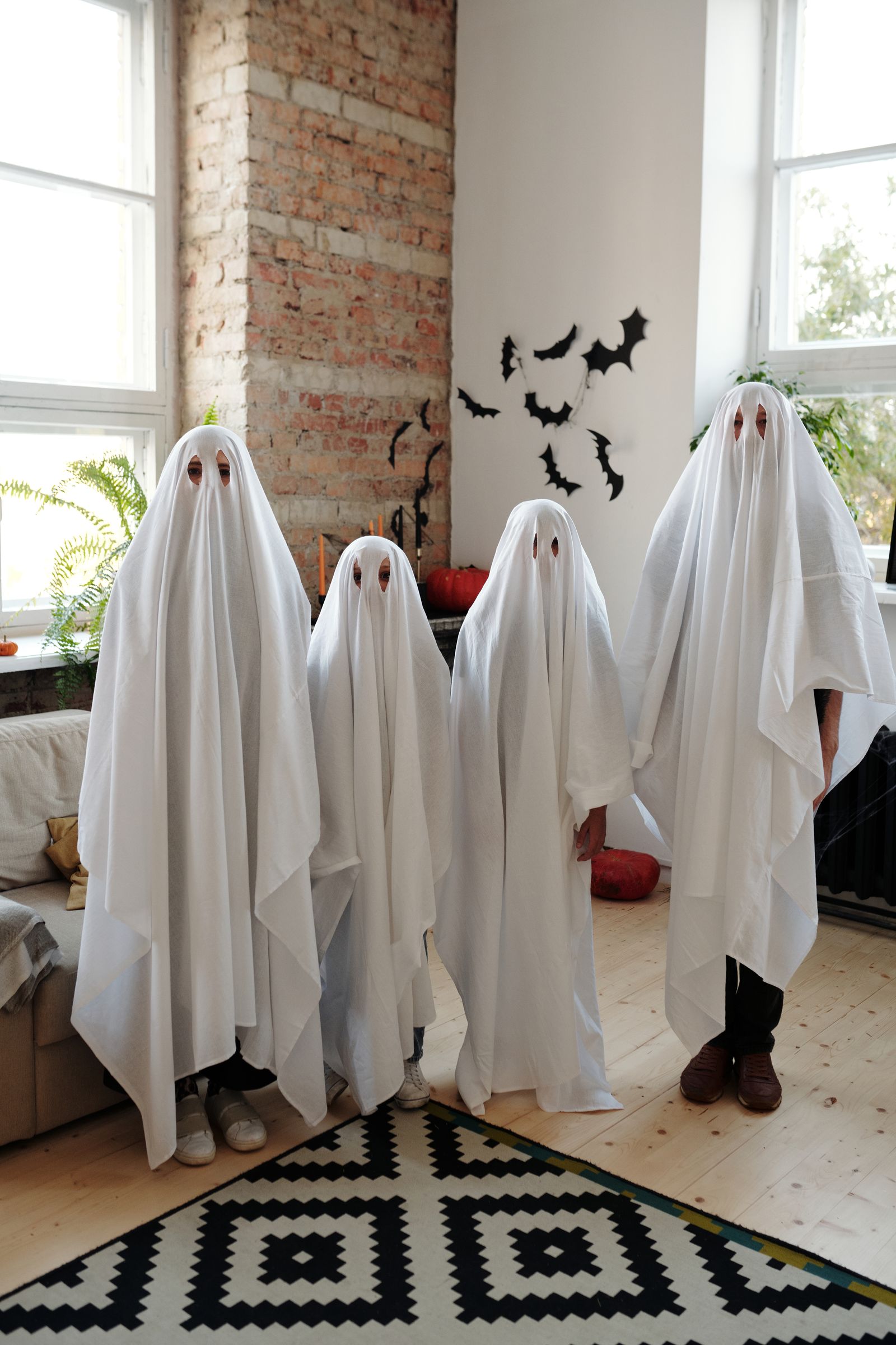 People in white-sheet ghost costumes inside a home