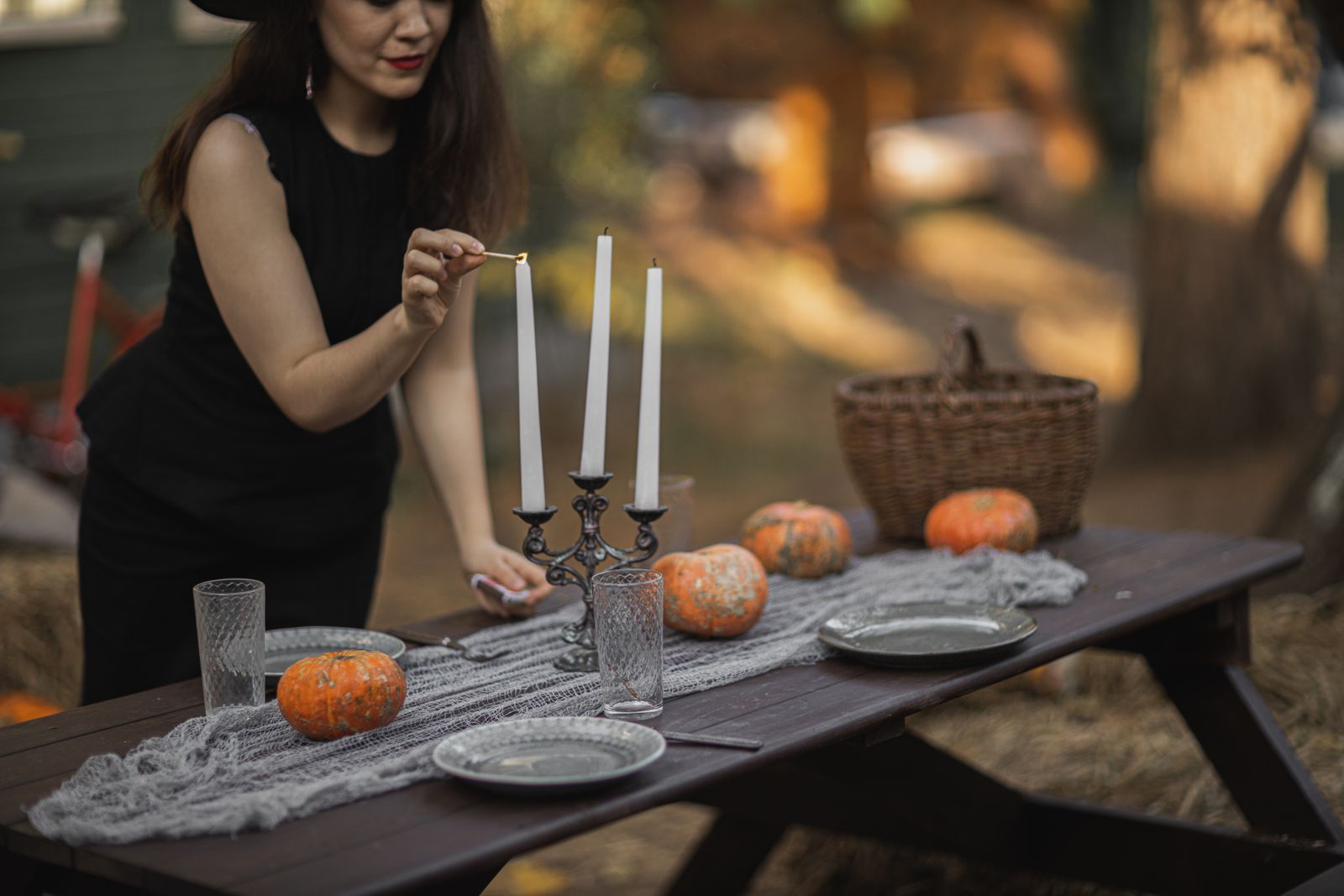 A person lighting candles on an outdoor autumn table