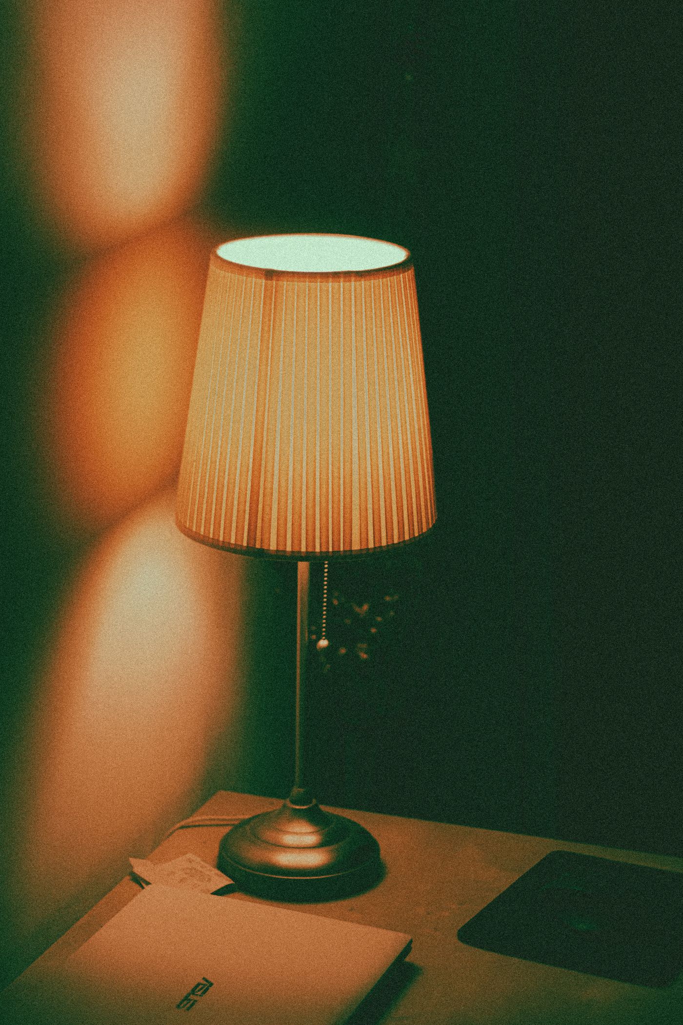 A warm table lamp beside a laptop in an evening workspace