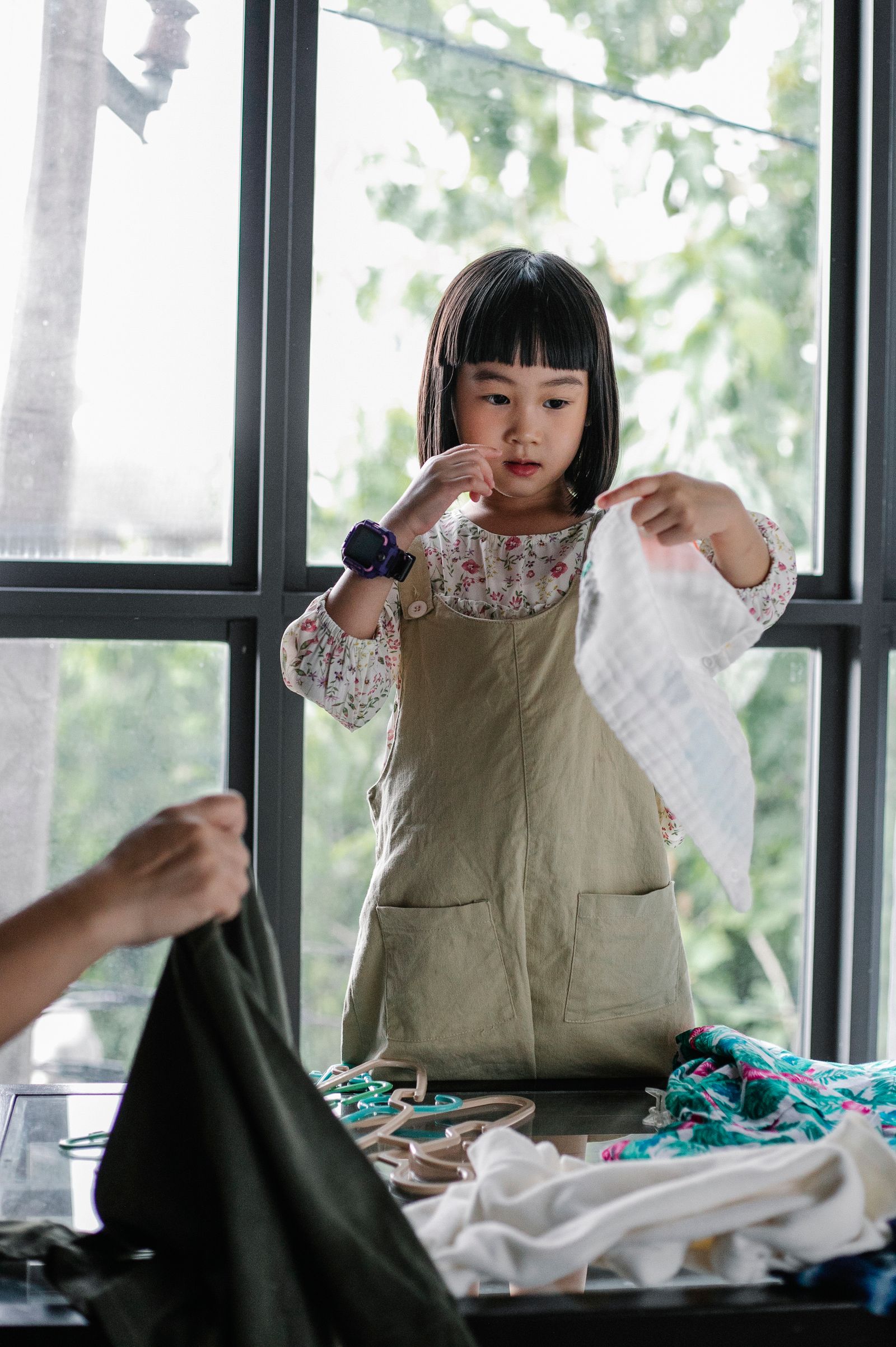A child lifting a light garment from a clothing group