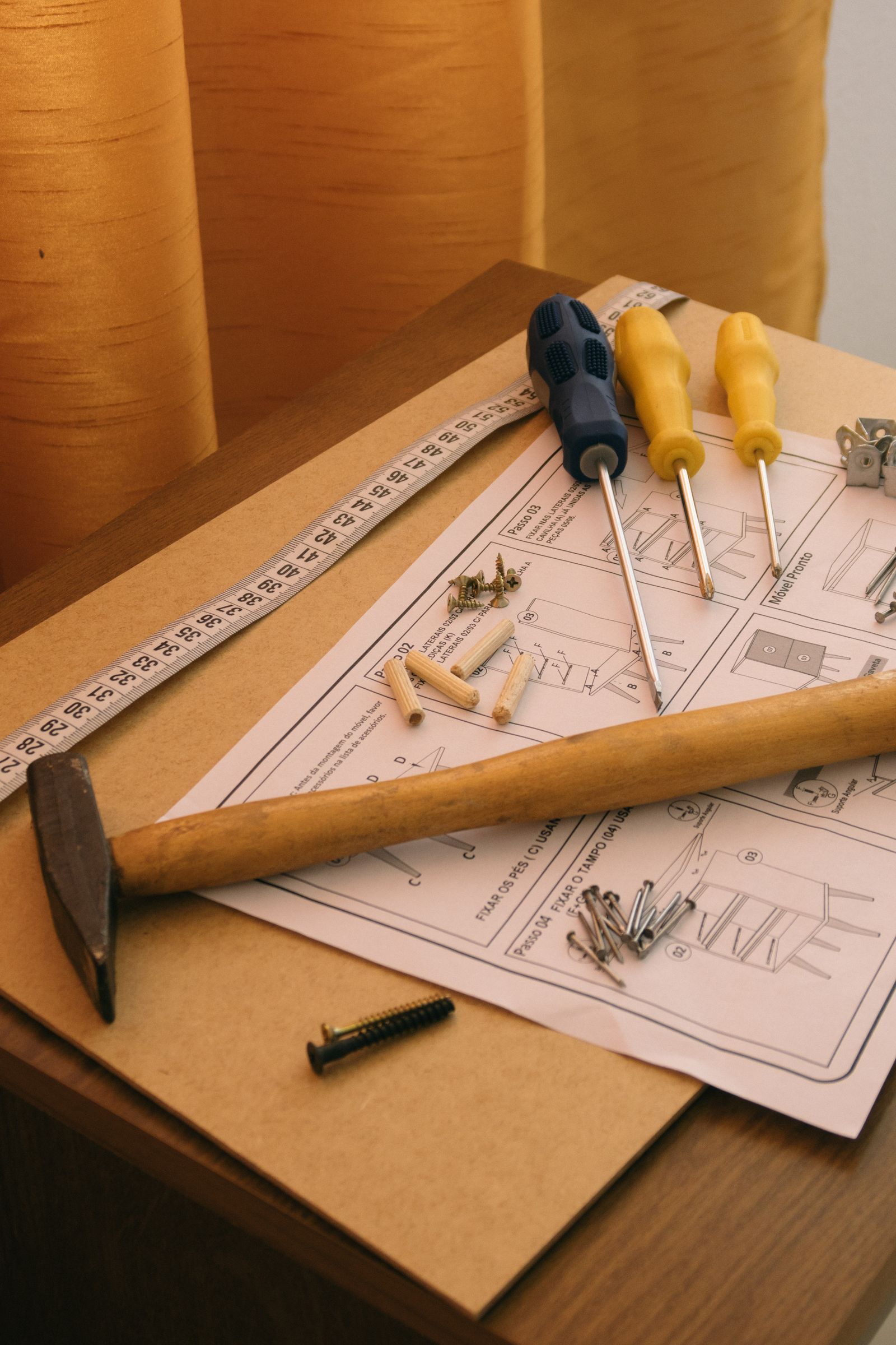 Assembly instructions with screwdrivers, a hammer, and small hardware