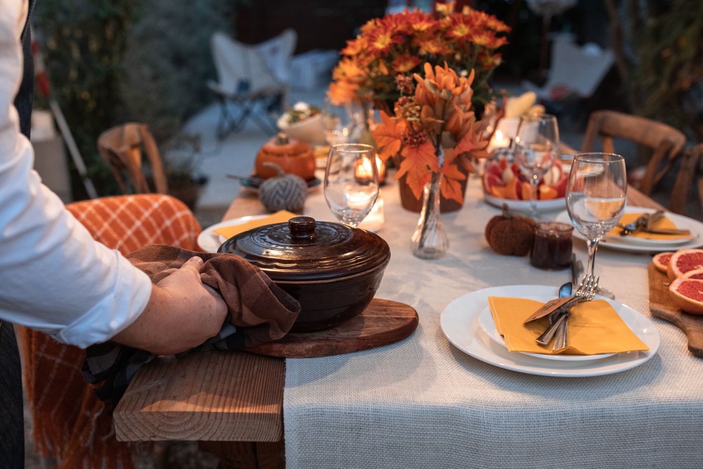 Person setting a pot onto a dining table during a gathering