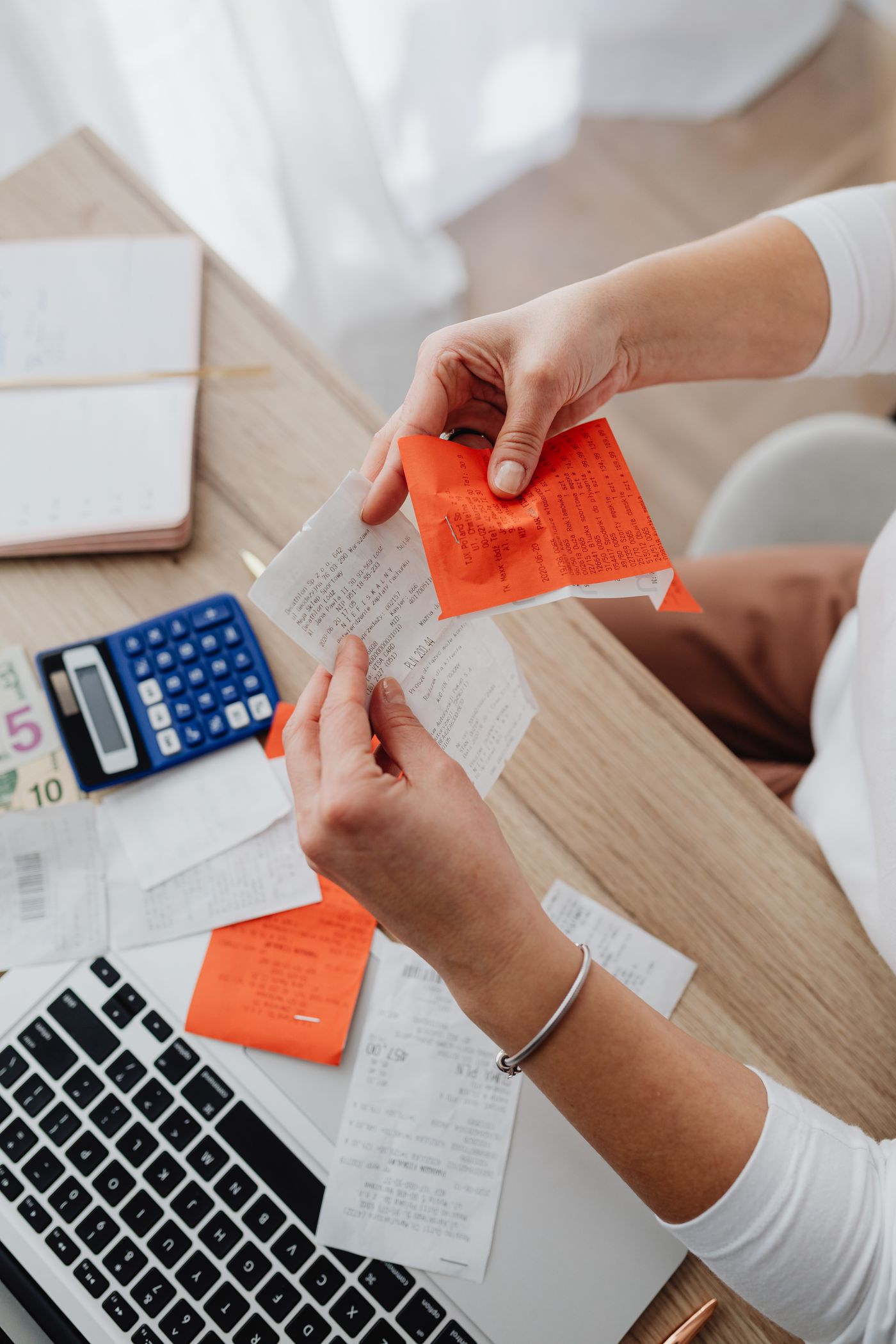 Hands holding a receipt beside household paperwork