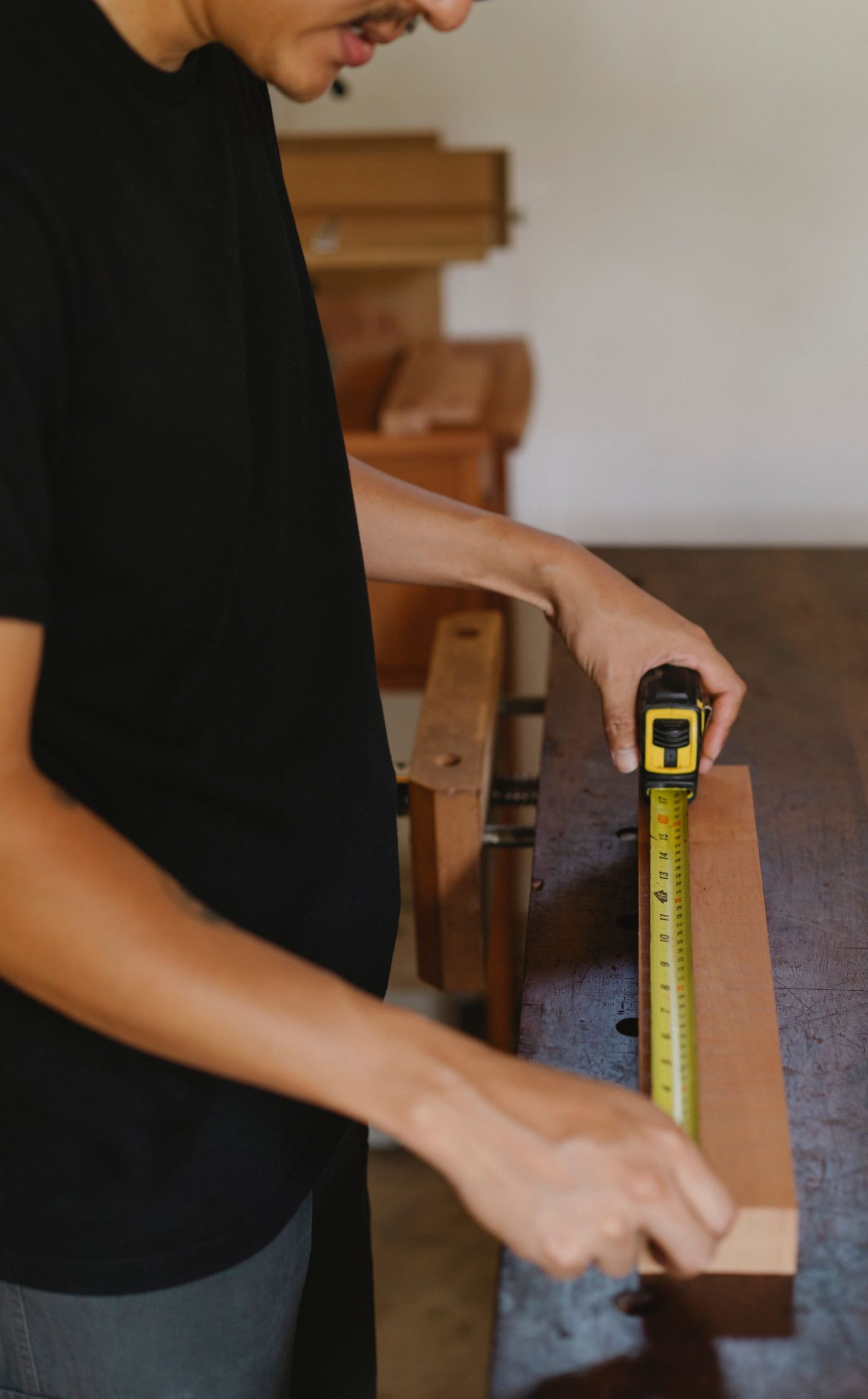 A person measuring a piece of wood with a tape