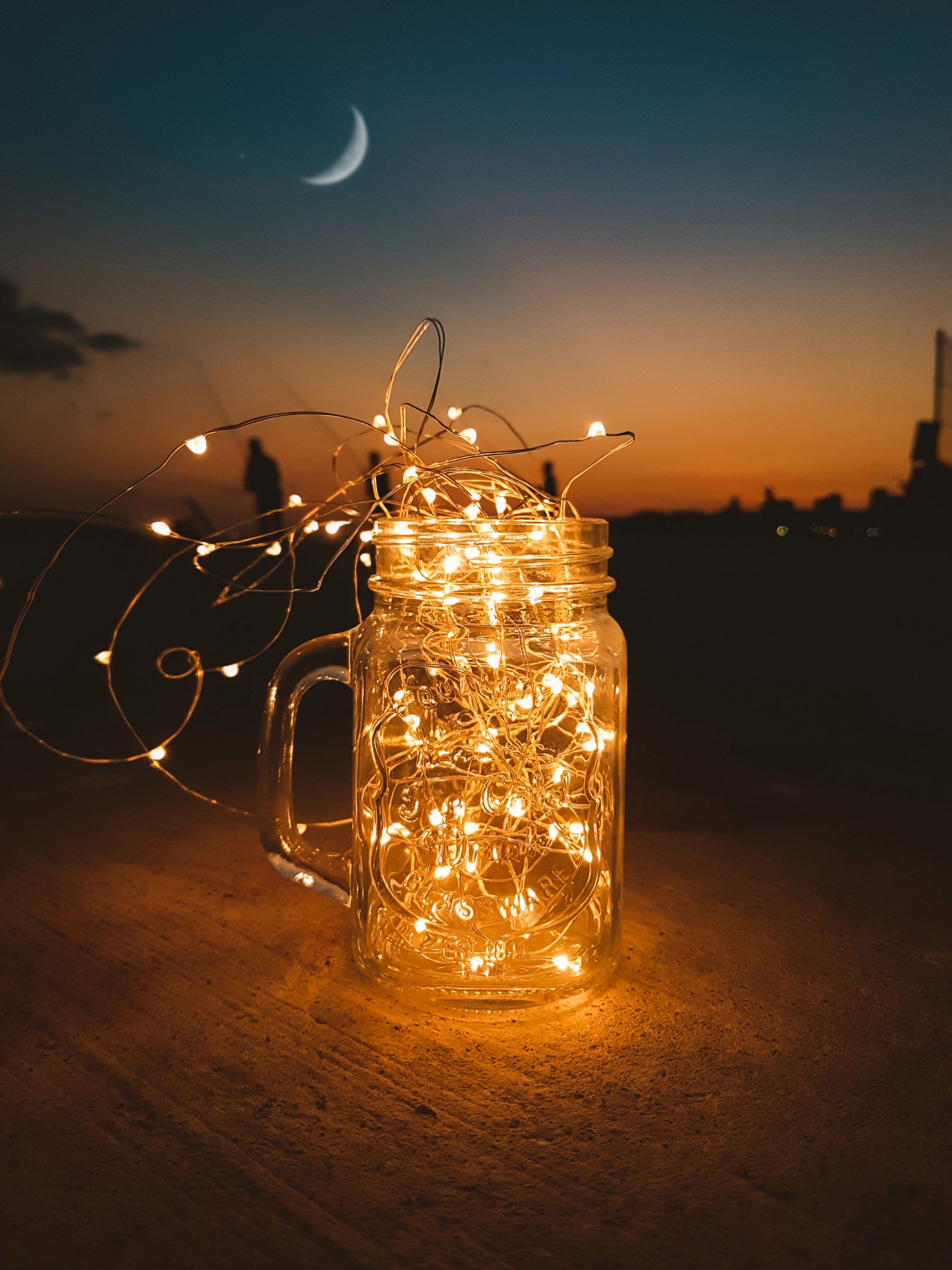 A glass jar filled with string lights at dusk