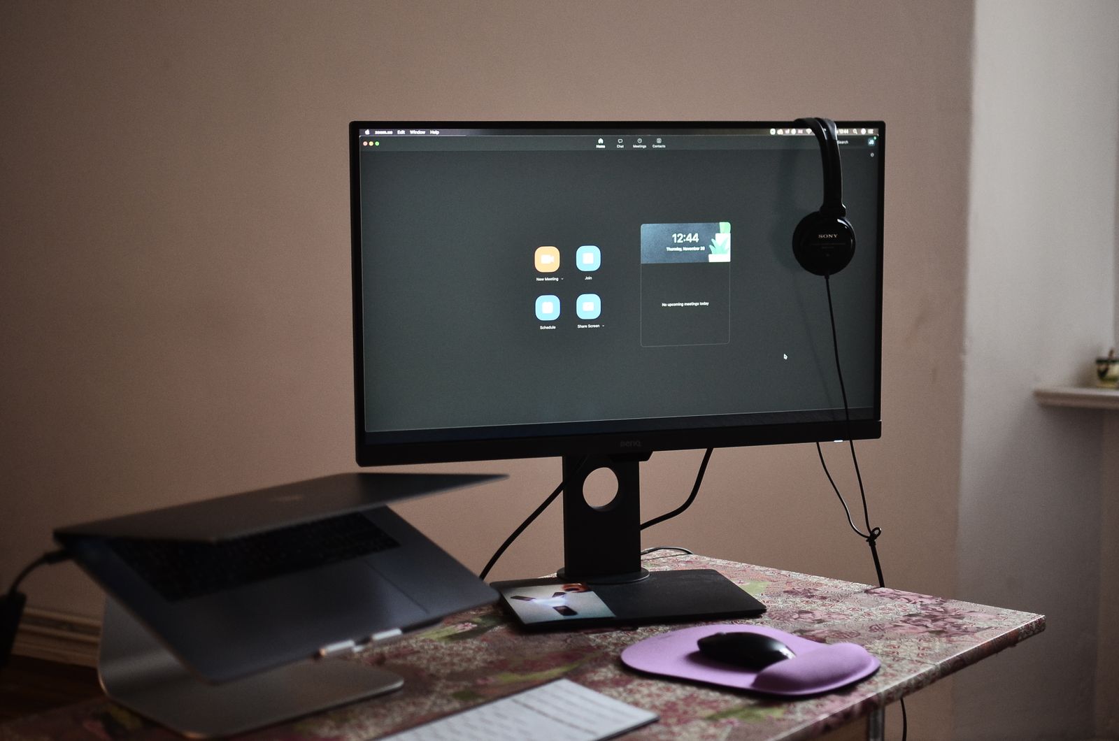 A monitor, headphones, keyboard, and laptop on a desk