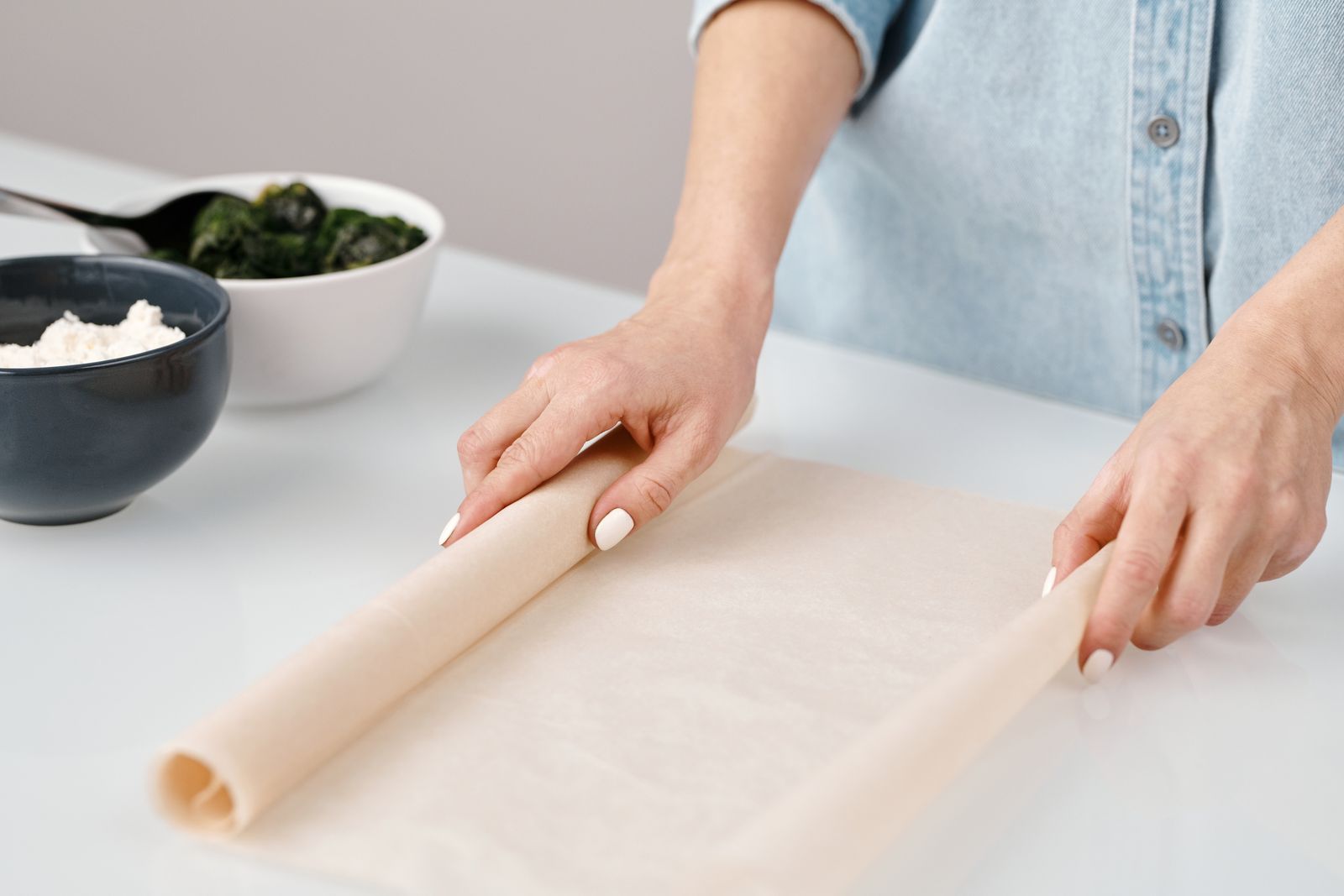 Hands rolling dough on a pale kitchen surface