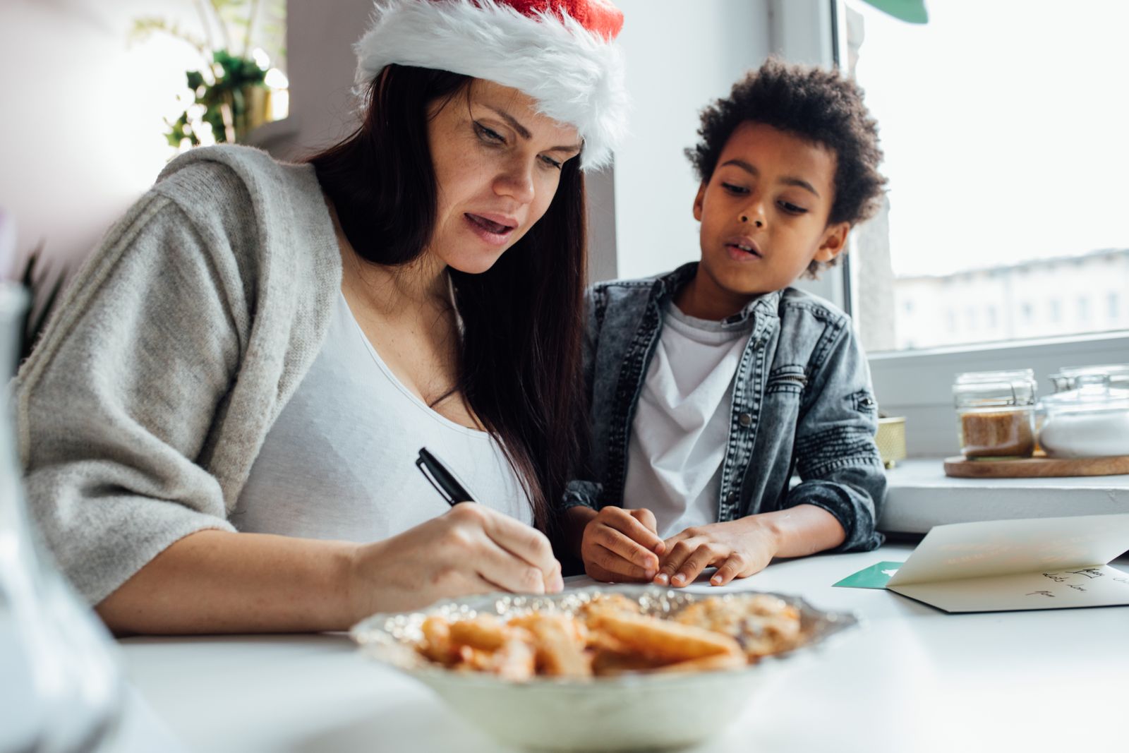 A parent and child writing together during Christmas