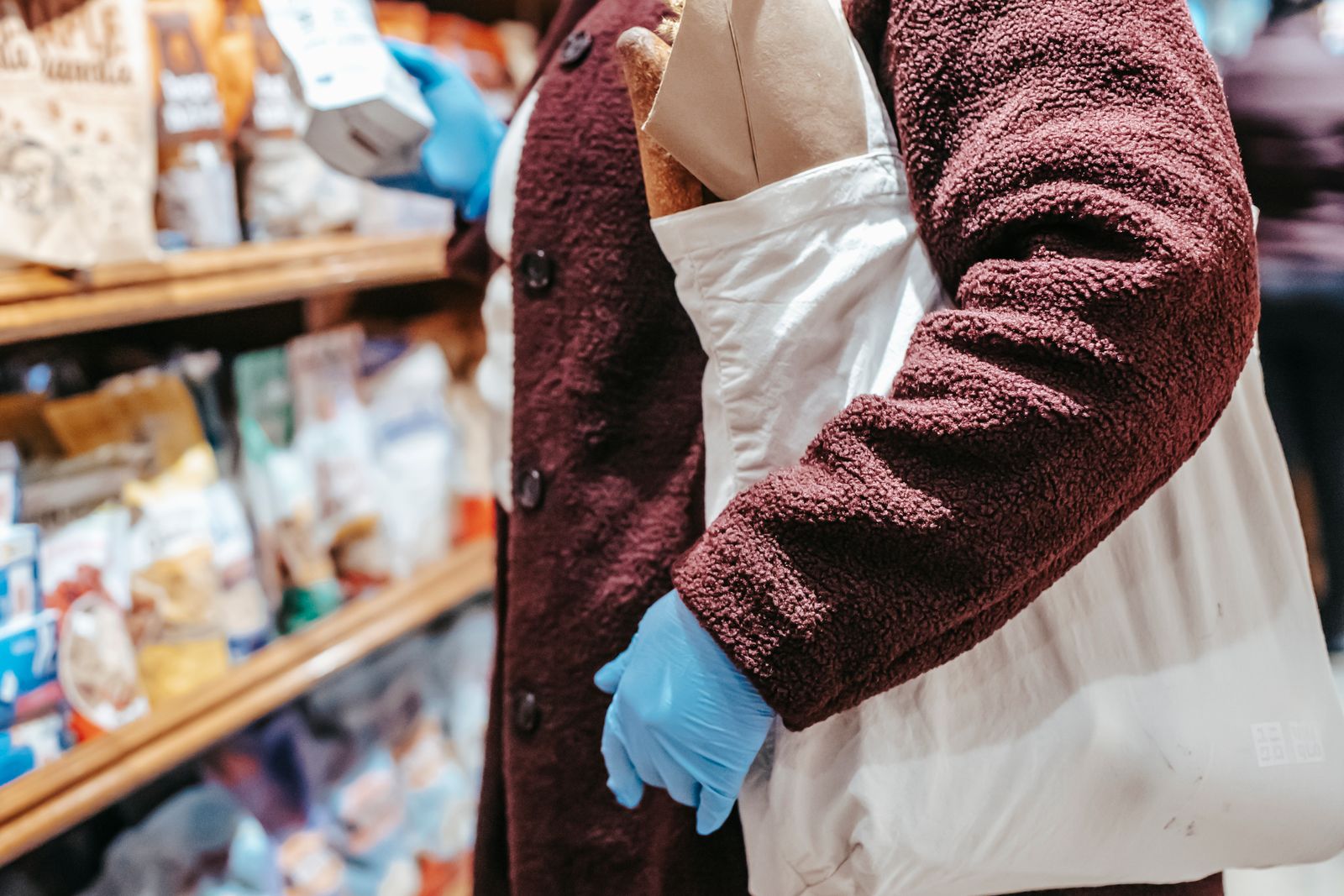 A shopper carrying a cloth tote in a grocery store