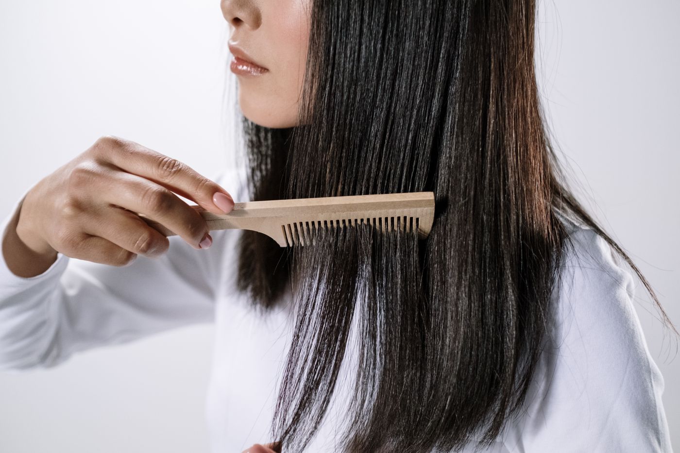 Person using a light-colored comb through long hair