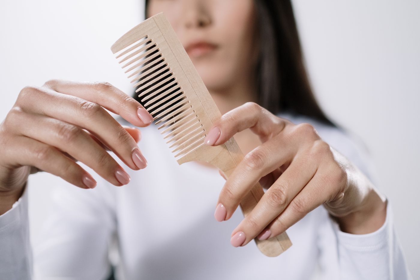 Hands holding a light-colored comb for inspection