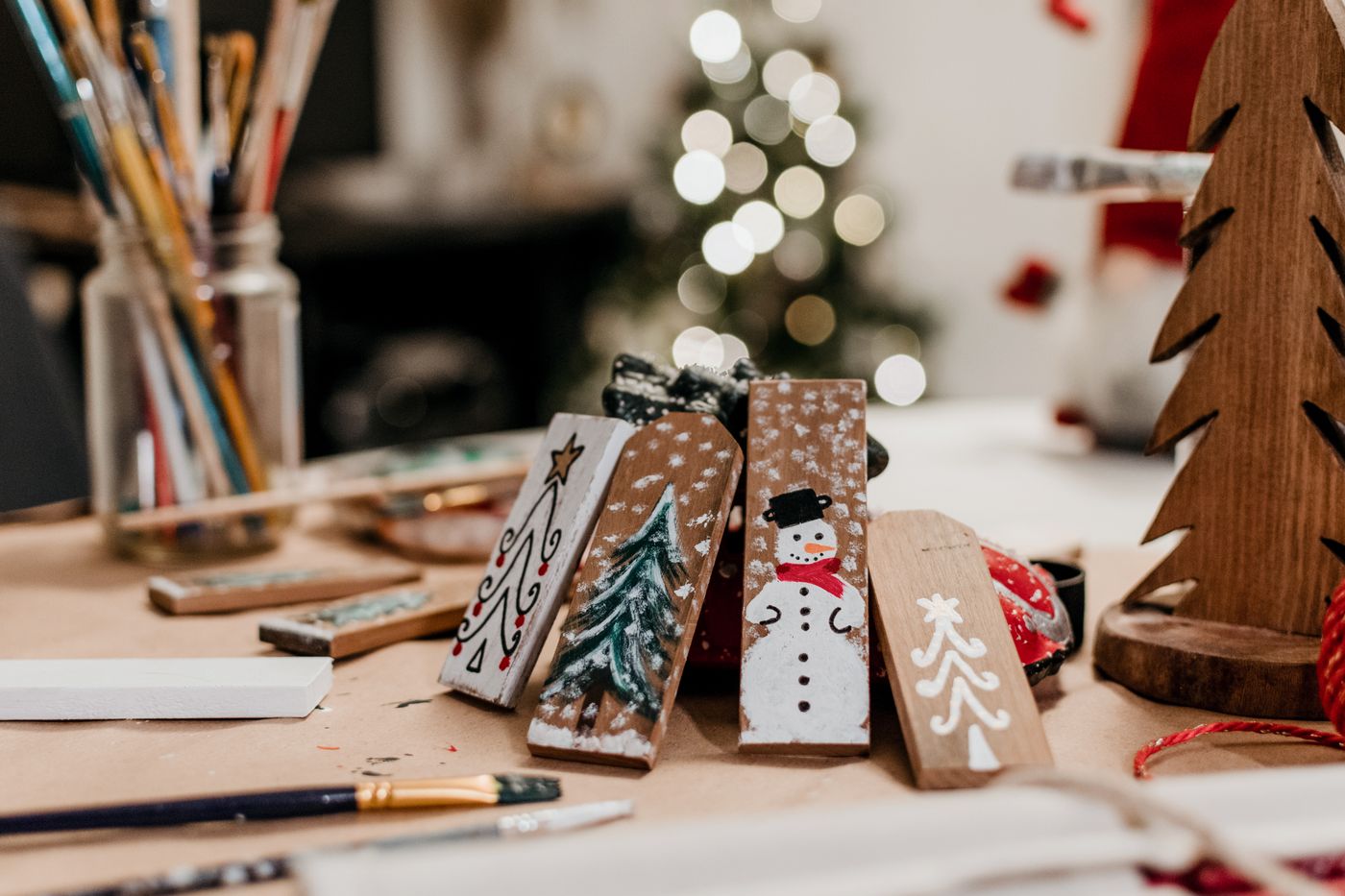 Painted wooden Christmas ornaments and brushes on a craft table; contextual inspiration, not Amosfun products