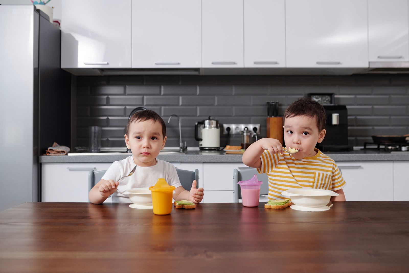 Two children eating at a table in a kitchen