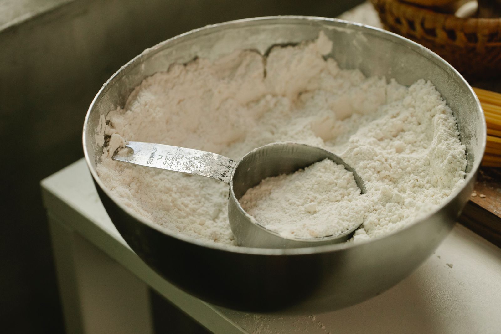 A metal dry-measuring cup resting in a bowl of flour