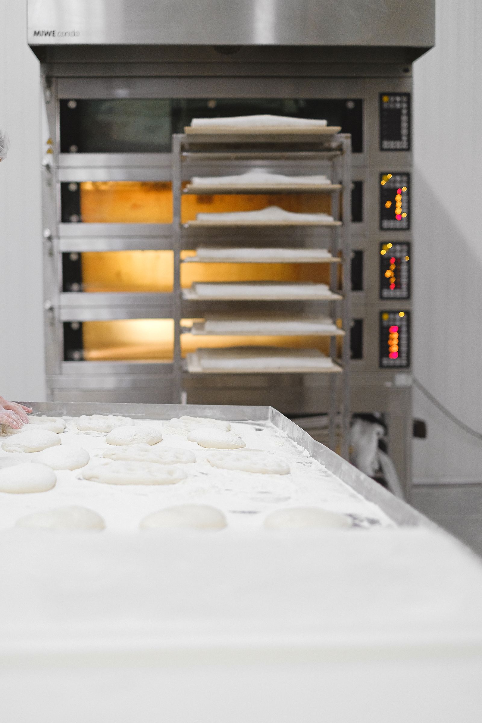 Dough preparation beside a large commercial oven containing trays